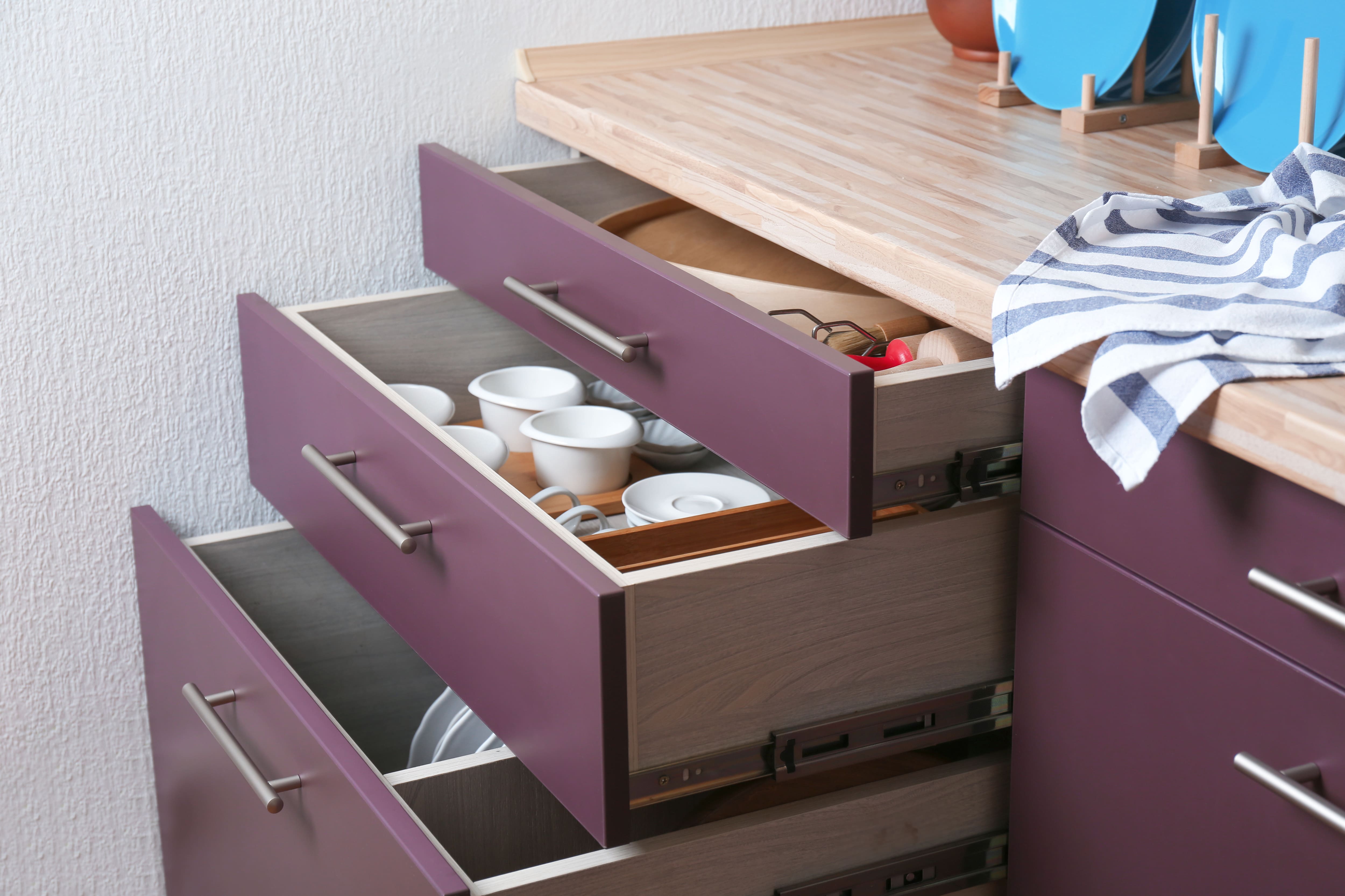 Vertical purple kitchen drawers in a corner with assorted tableware