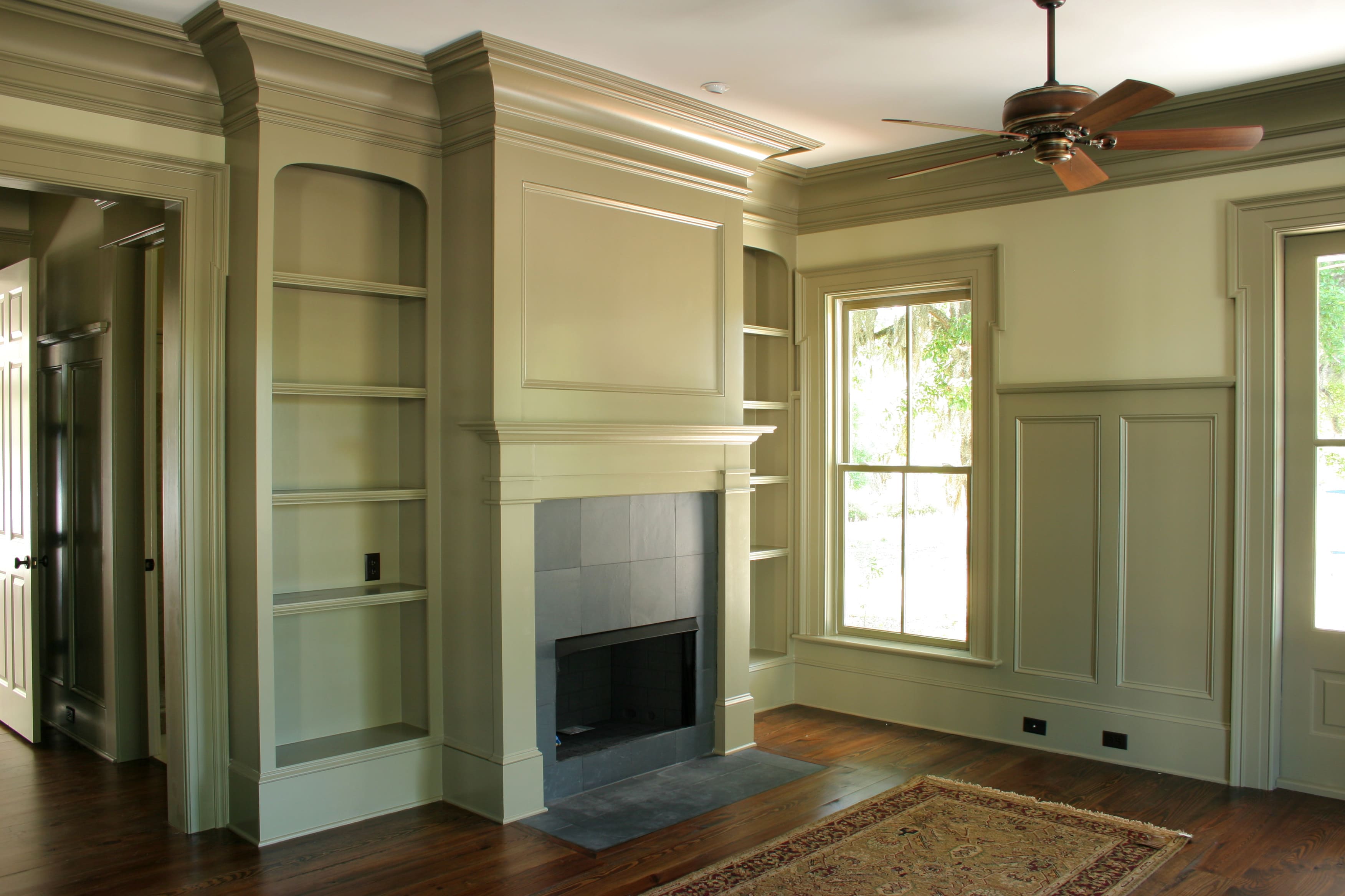 A large living room with a light green colored wainscoting and crown molding