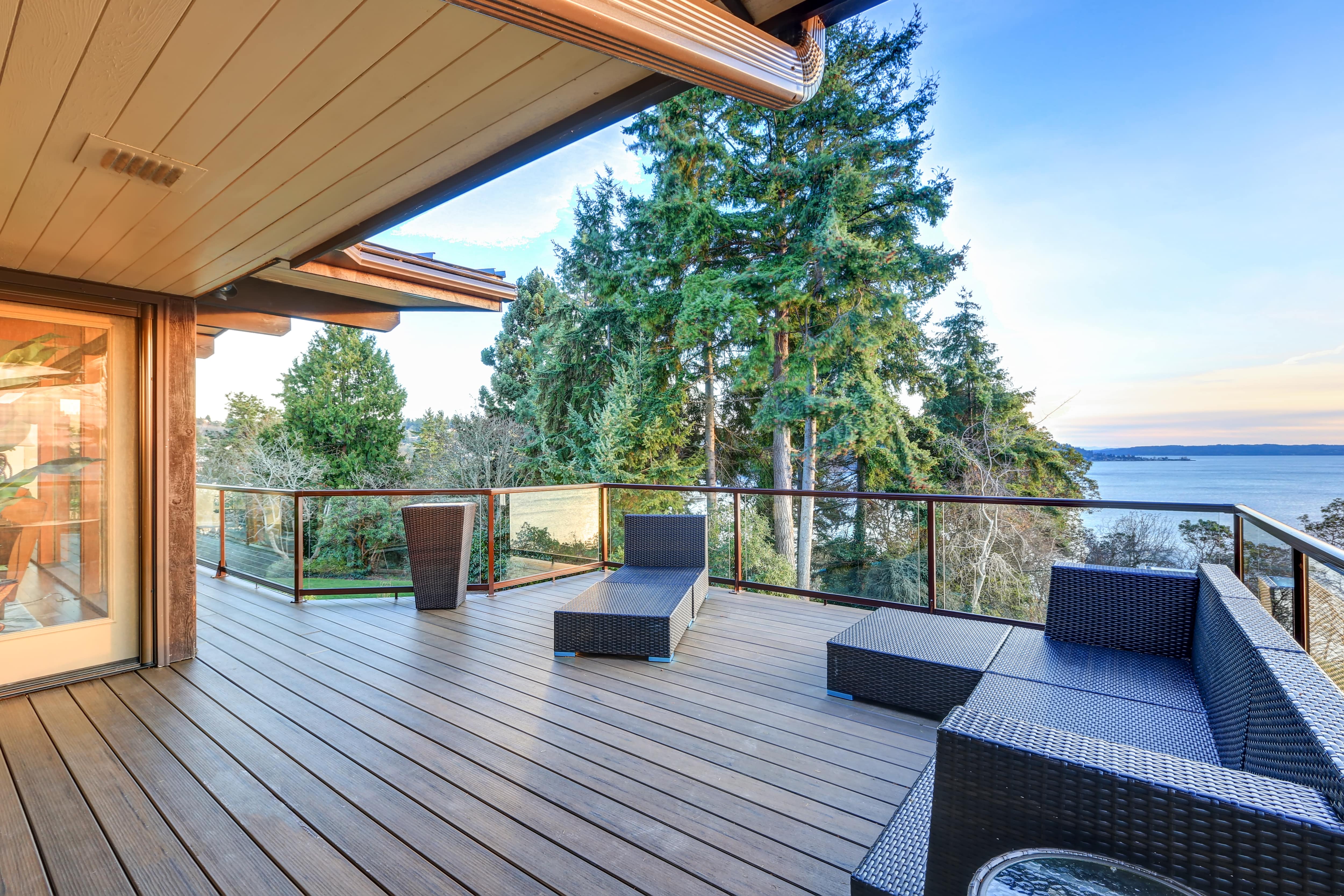 Home patio with glass panel railing overlooking the water