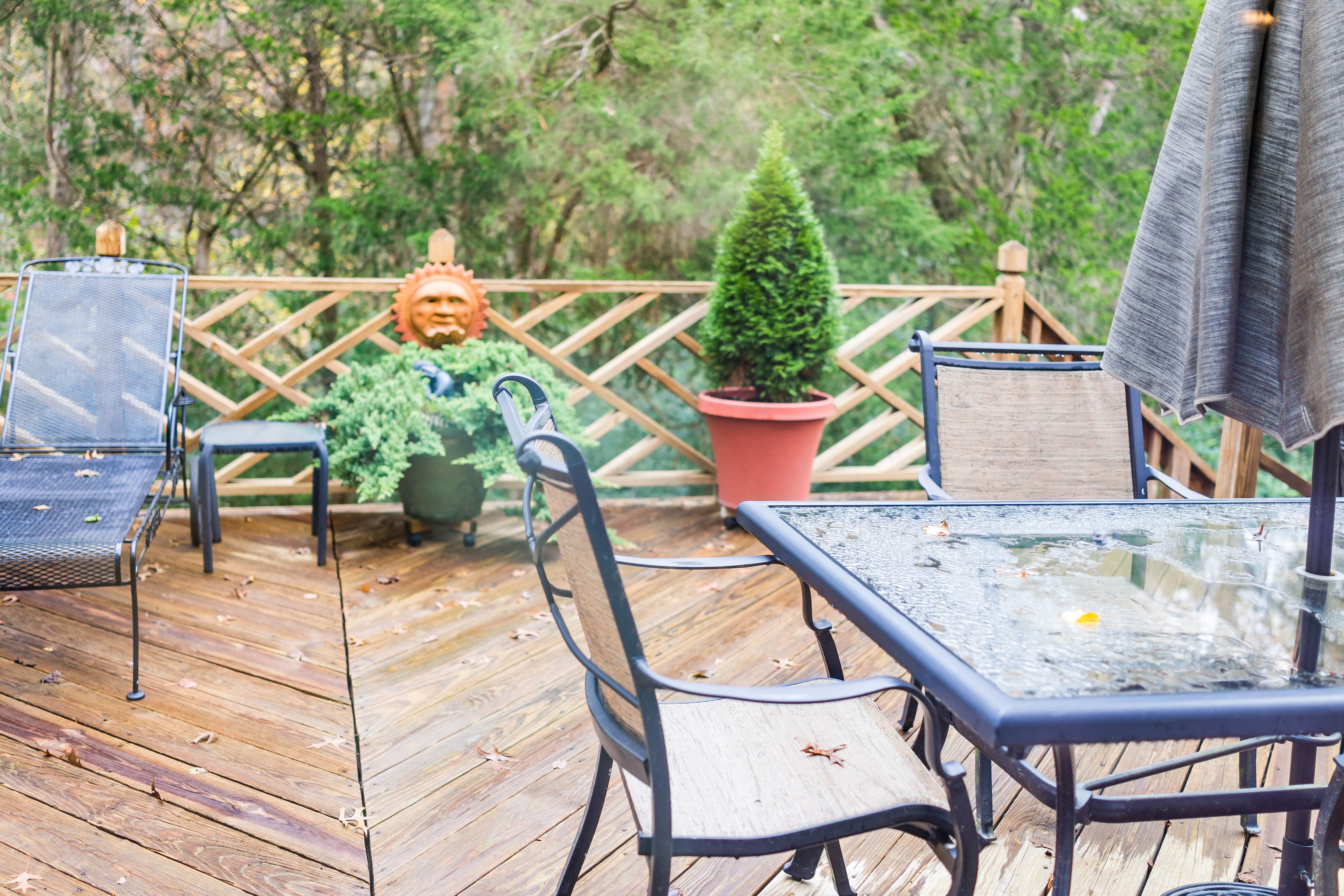 Wooden patio with geometric railings, plants, and black iron tables and chairs