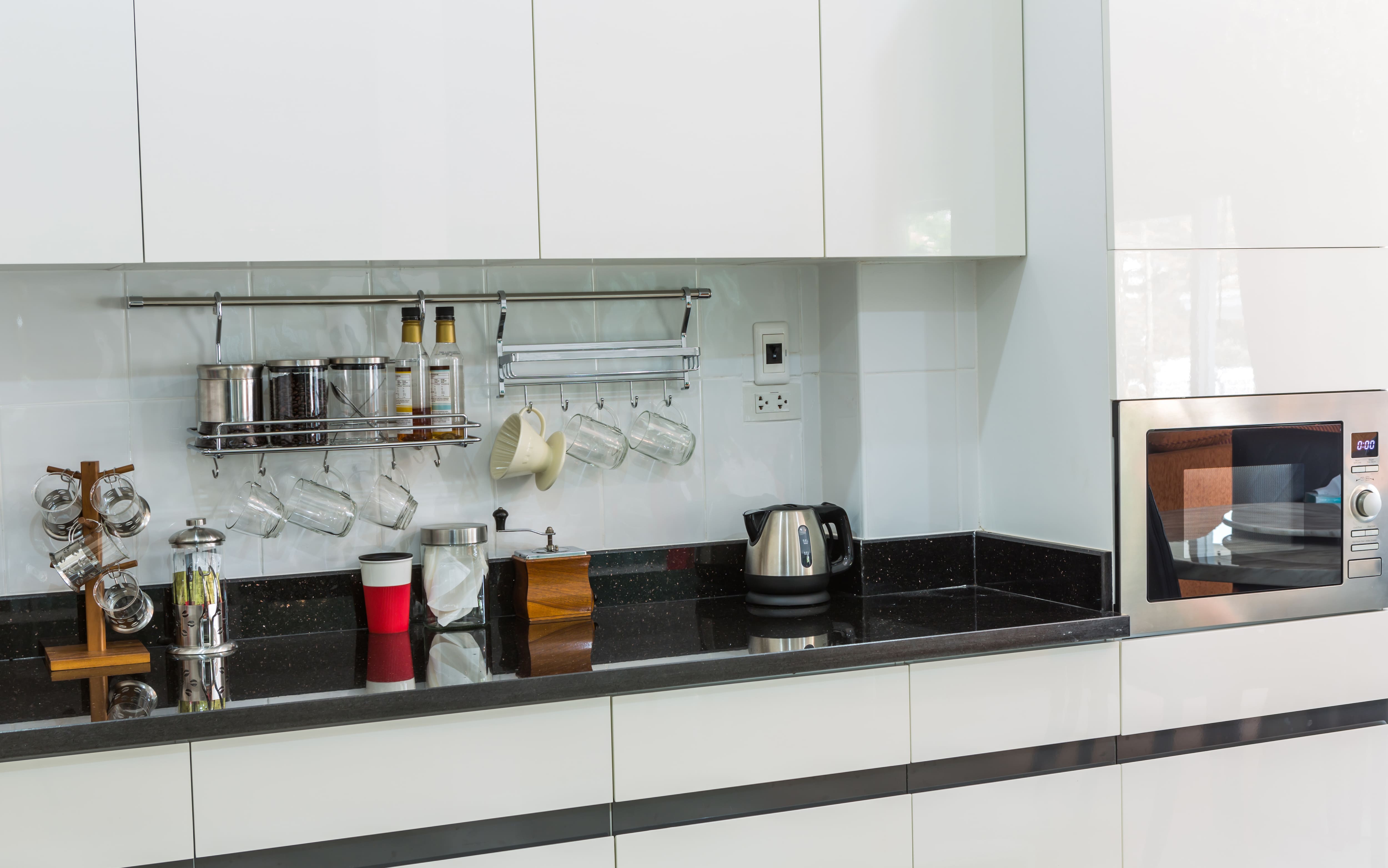 A kitchen countertop with a hanging bar for glassware and general accessories