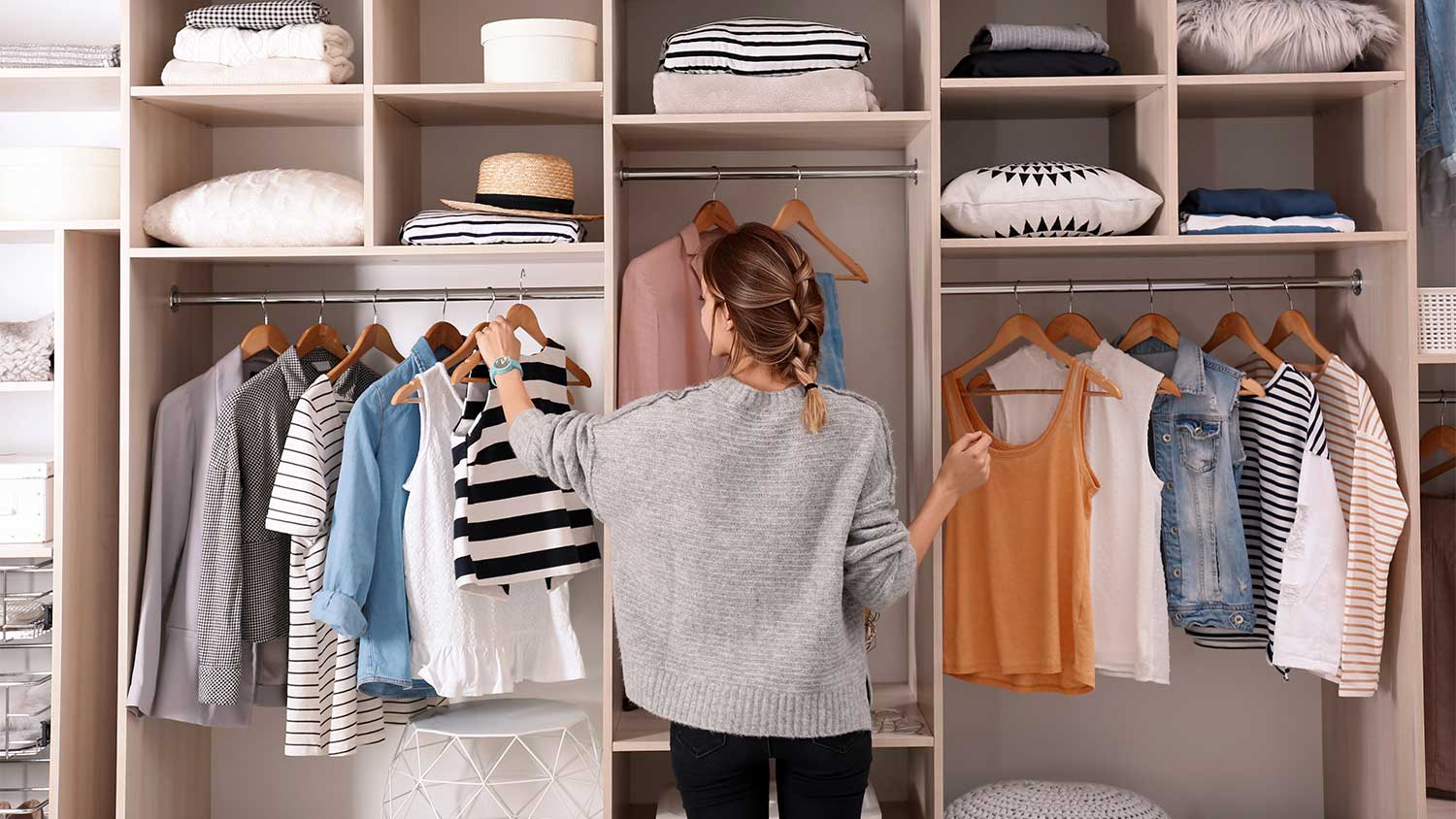 Woman choosing a sleeveless top from her closet