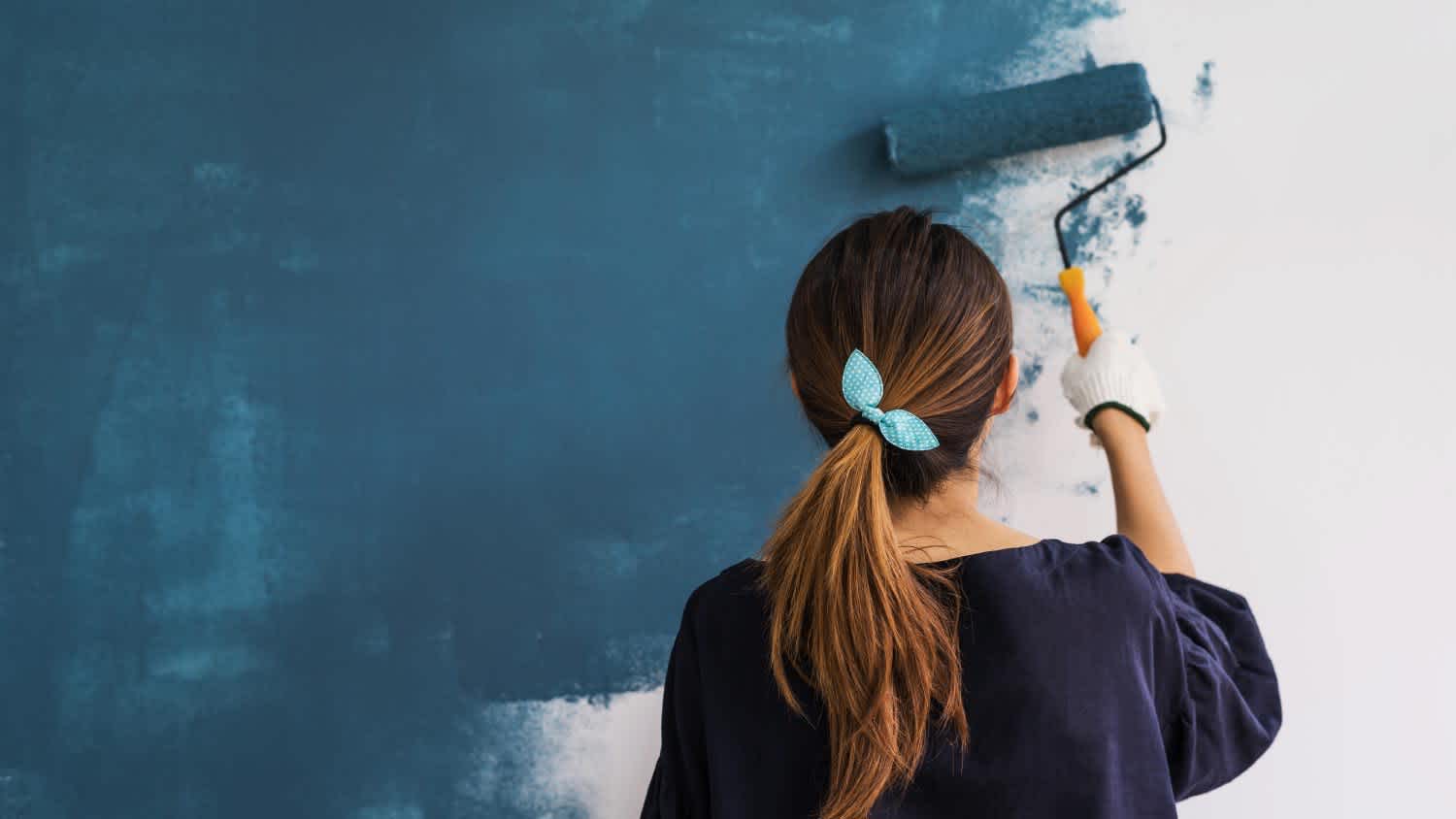 woman painting wall blue