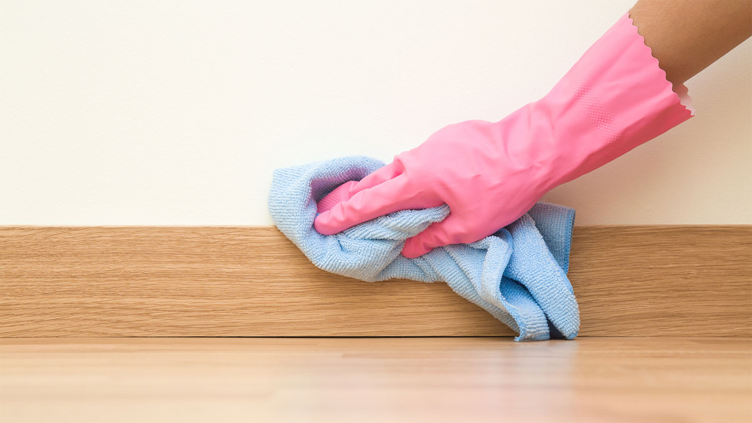 A closeup of a hand cleaning a baseboard
