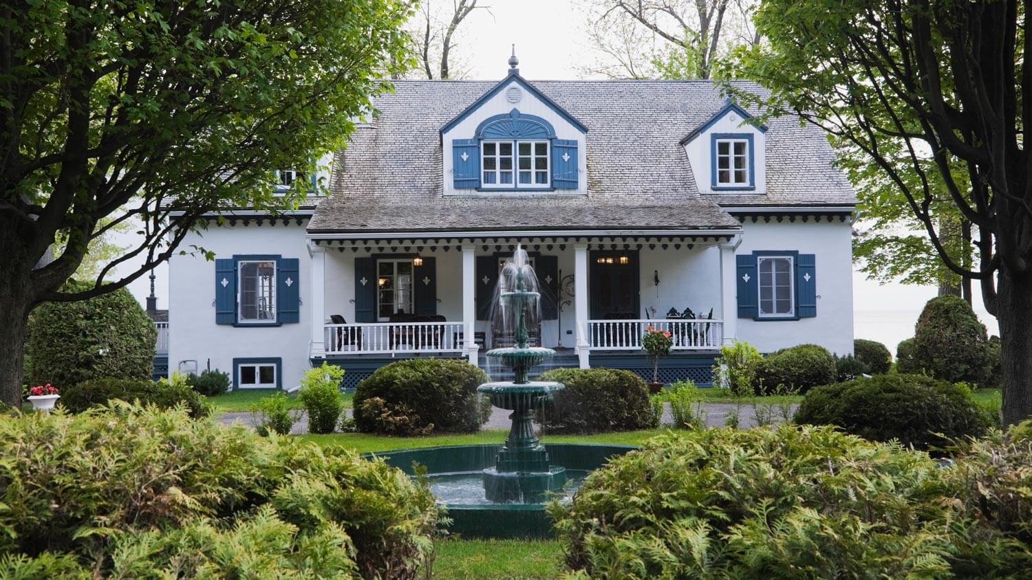 A cottage house facade with a water fountain in the yard