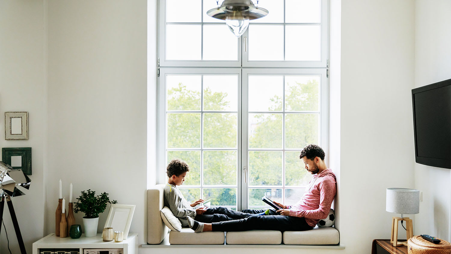 A father and child read by a window