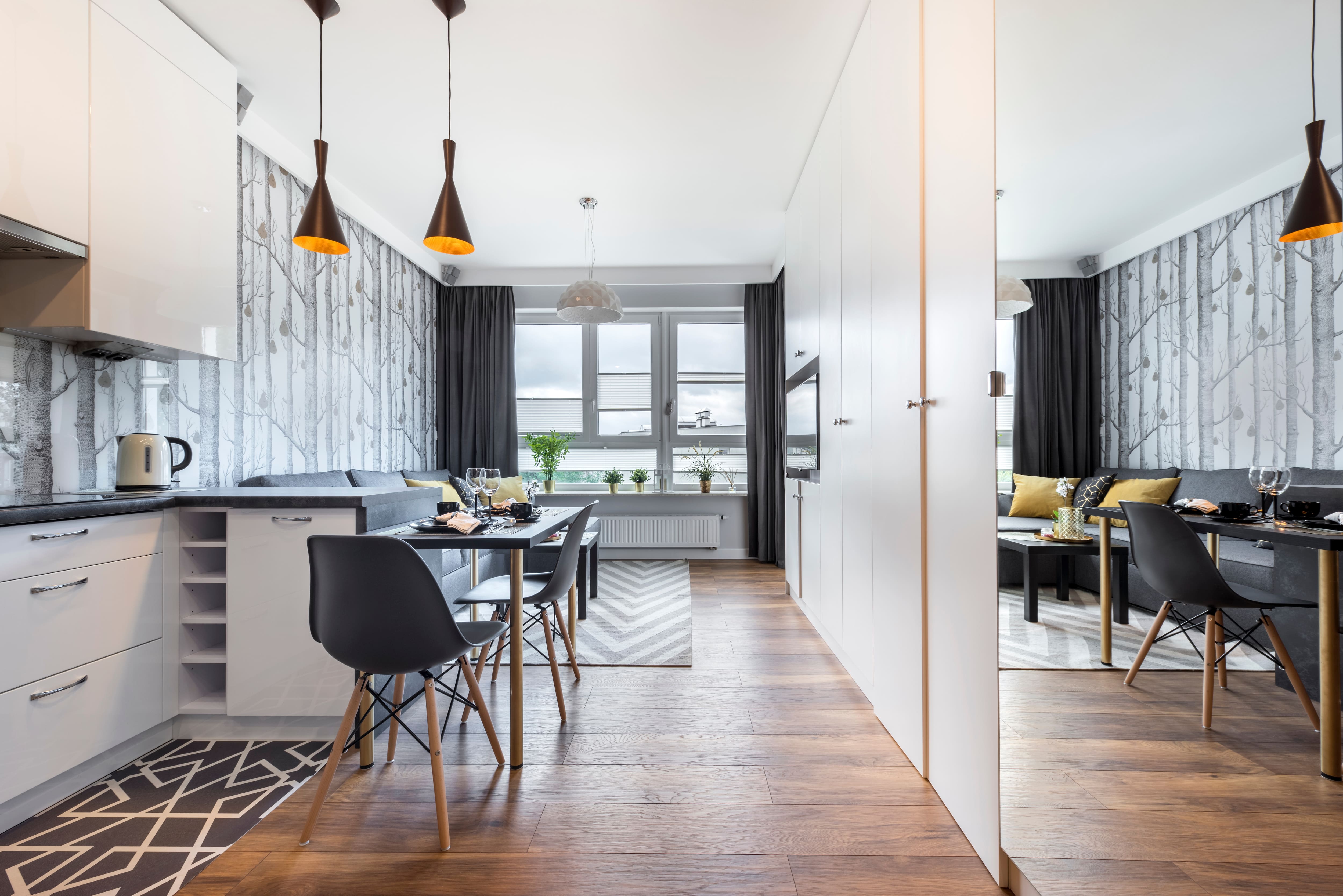 A narrow kitchen is reflected in a mirror making the space look larger