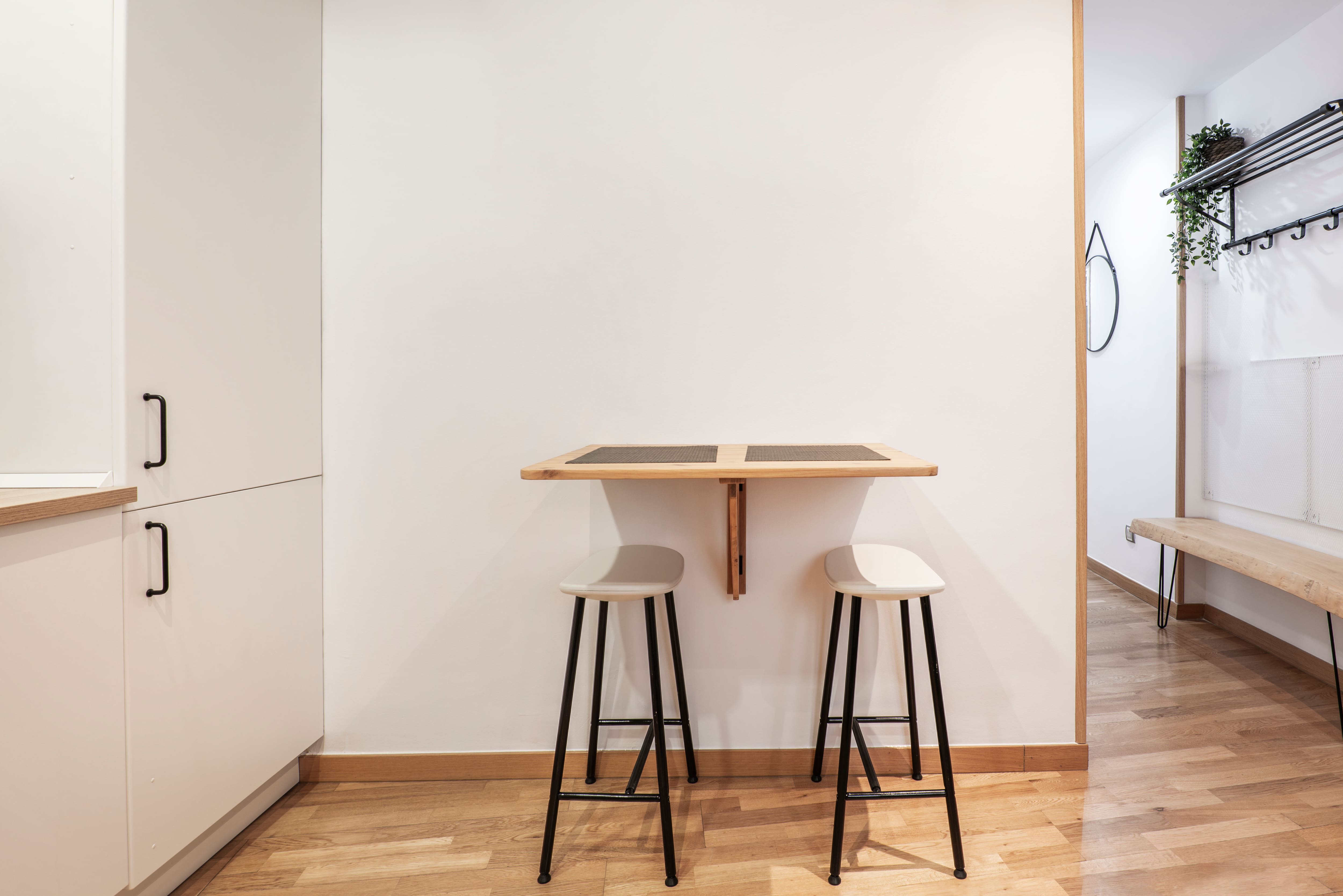 A small kitchen with a wooden drop-leaf table and small chairs