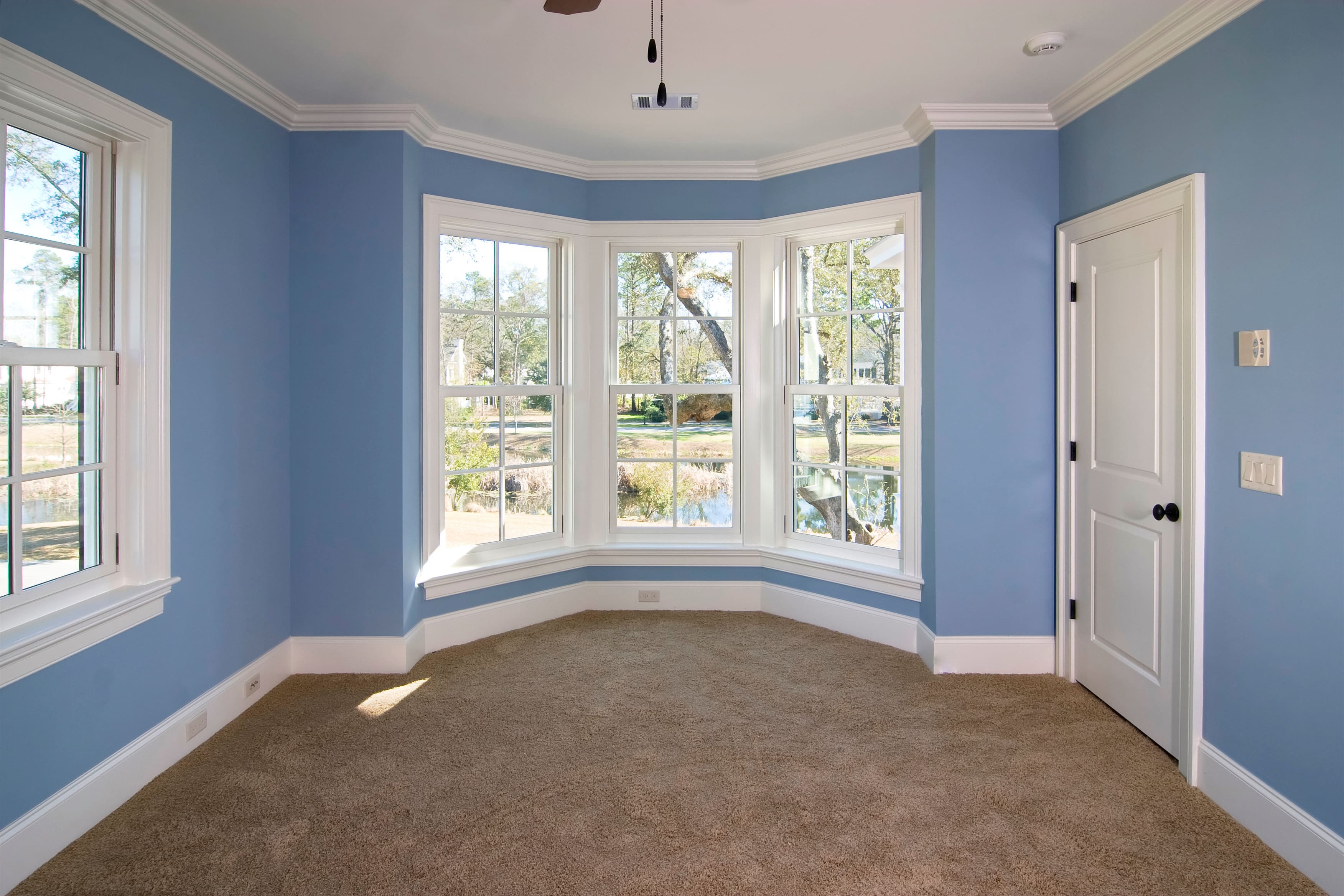 A bedroom with crown molding-framed windows