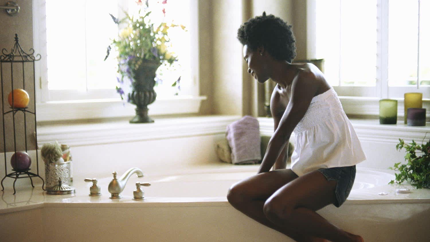 A woman sitting on edge of bathtub