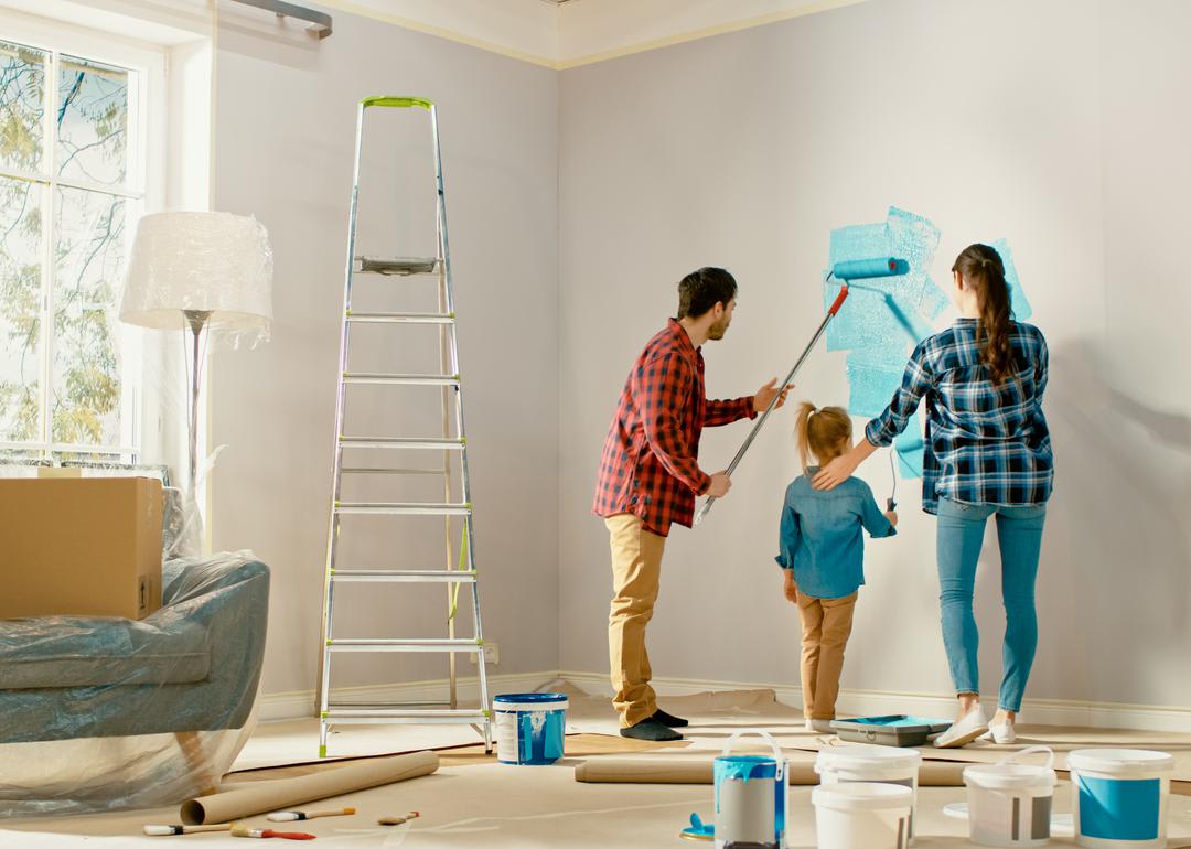 A family painting a wall with blue paint