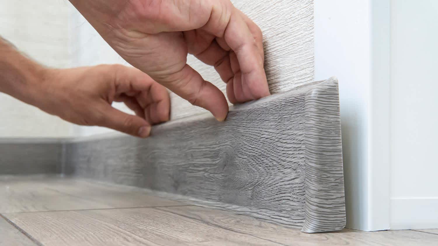 Close-up of a hand installing a baseboard