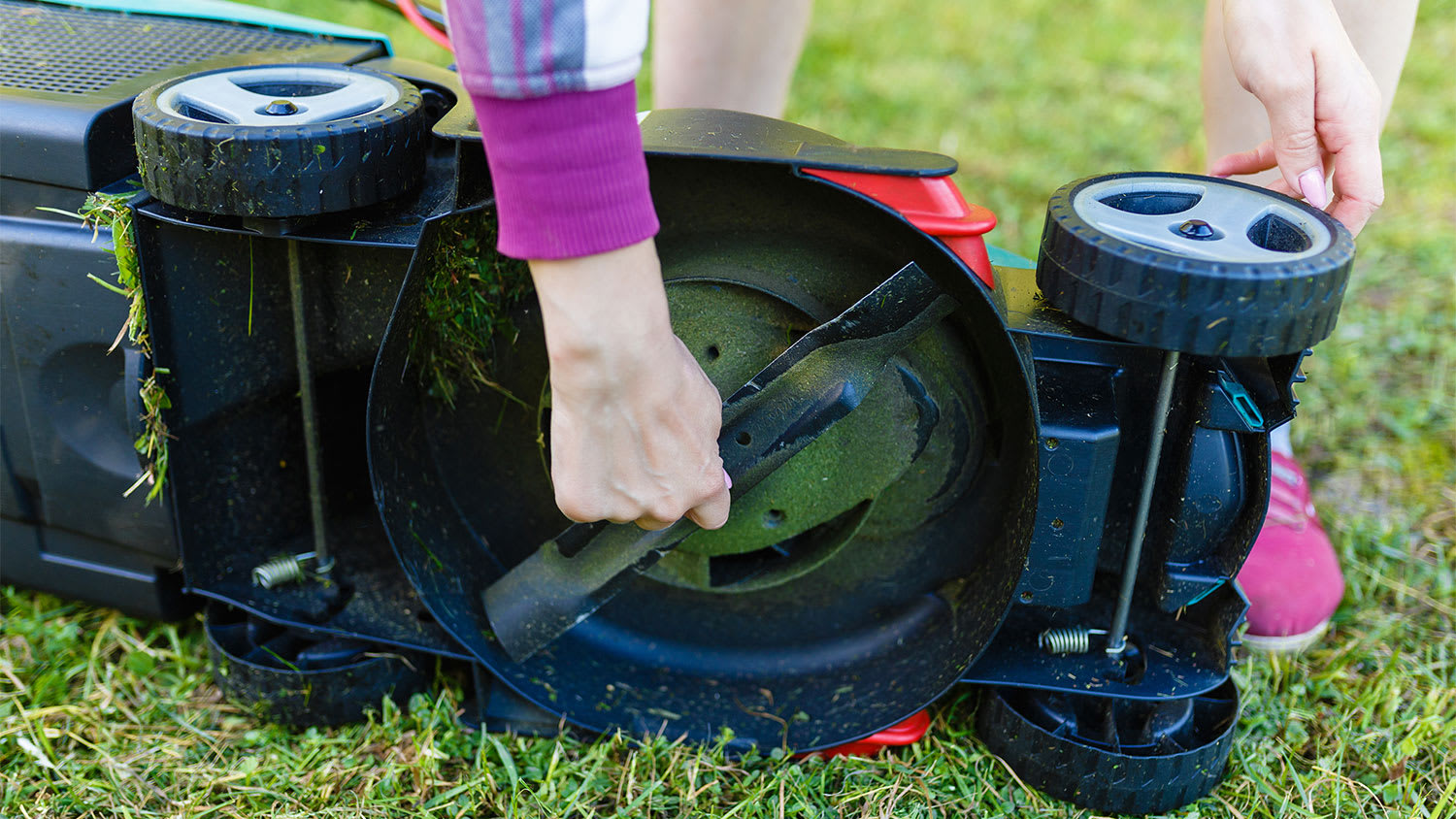 woman removing blade from lawn mower