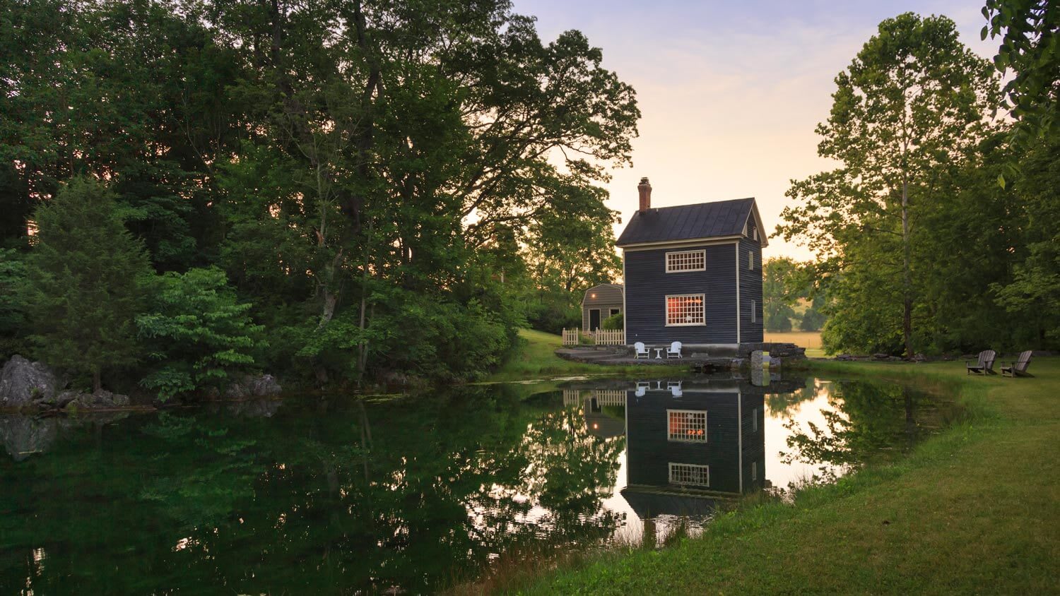 A cottage house next to a beautiful pond