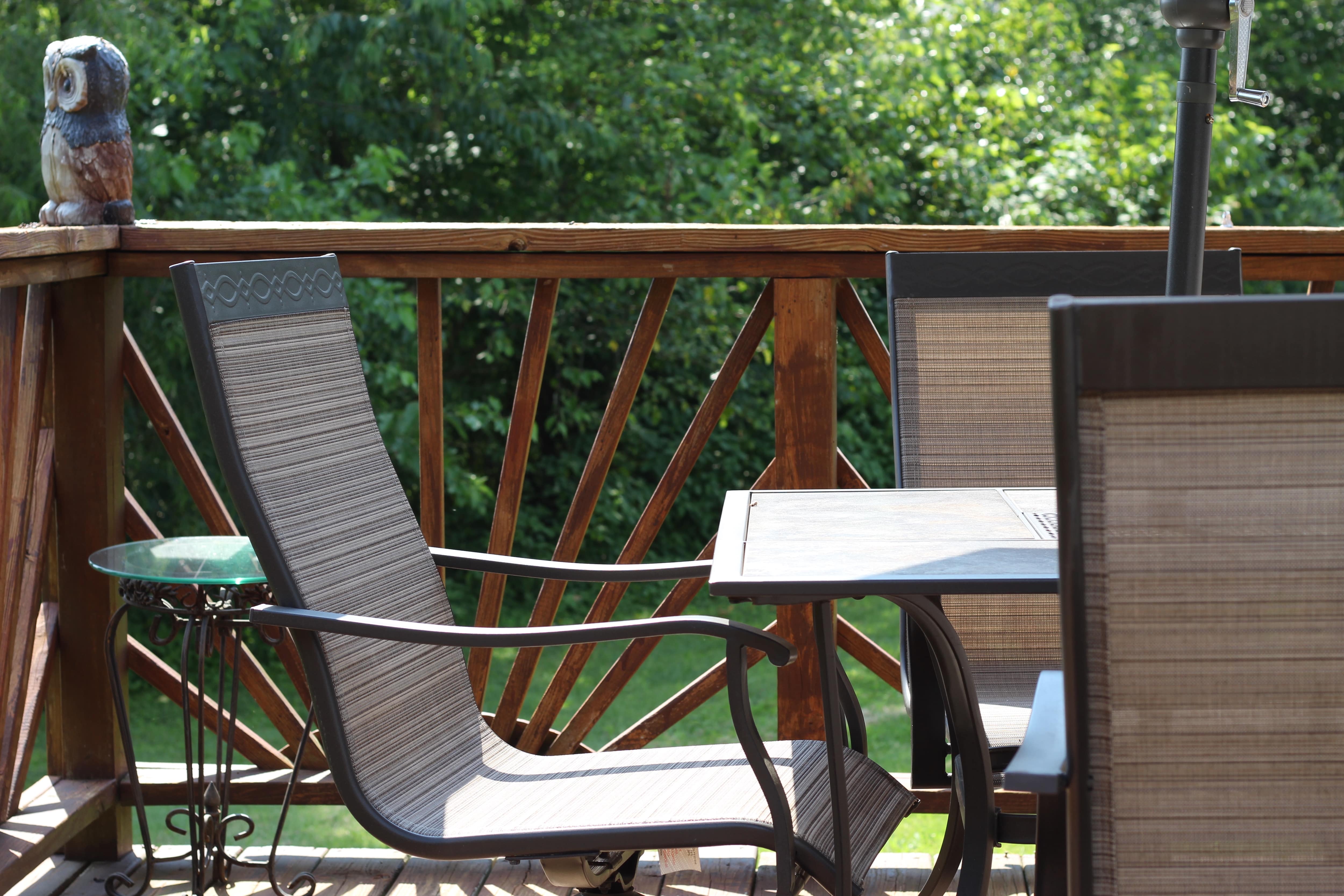 Patio with brown and black tables and chairs, a small glass table, and sunburst wood deck railings