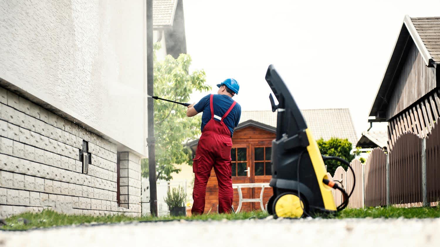 A man power washing a house’s exterior