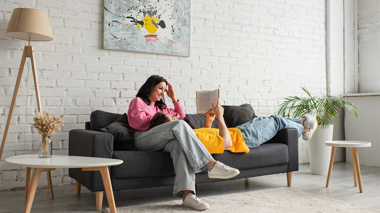 Couple sitting on a couch reading a book