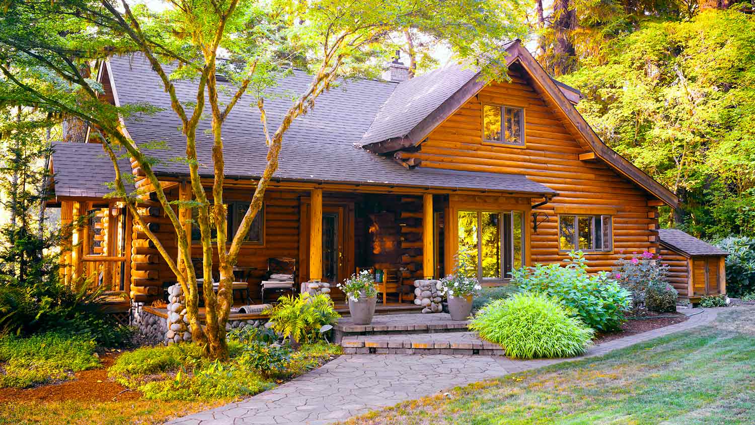 Log cabin in forest with mature landscaping