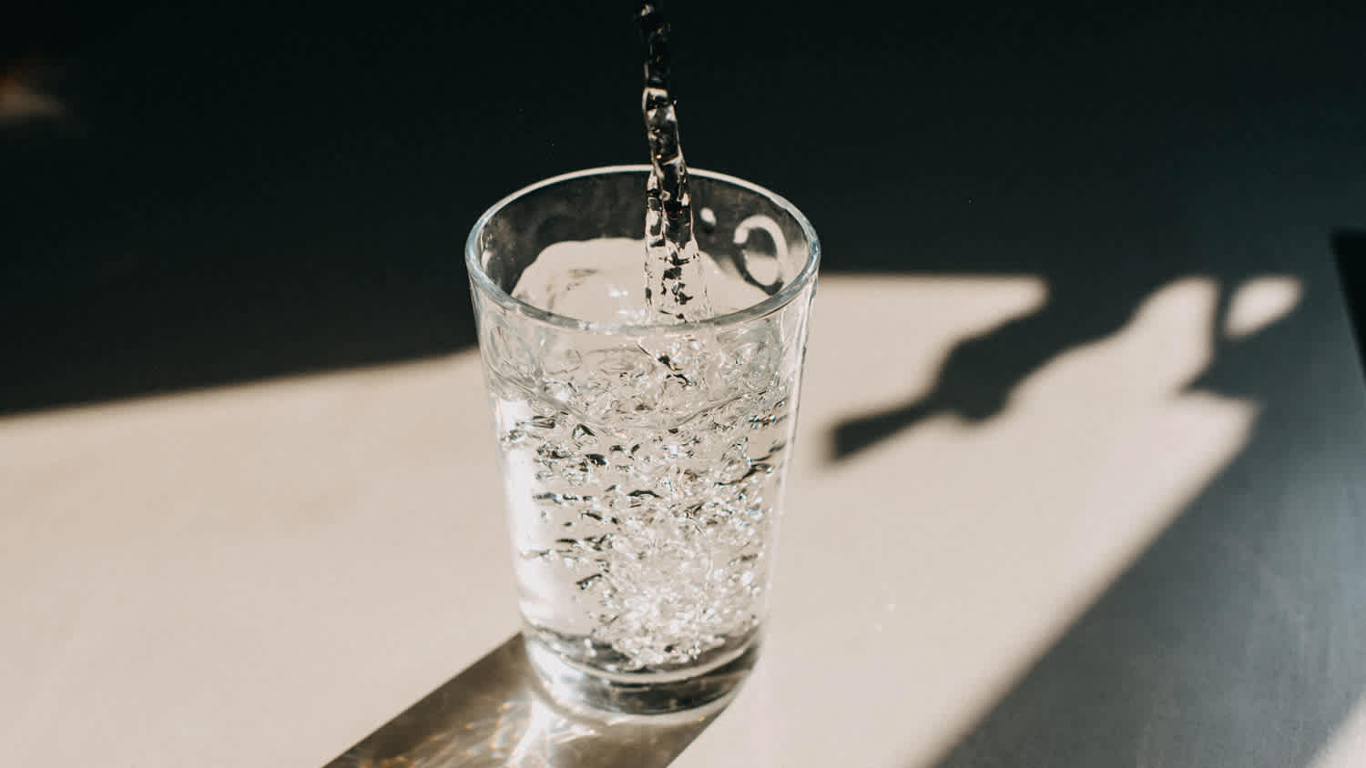 Water being poured in a sunlit glass
