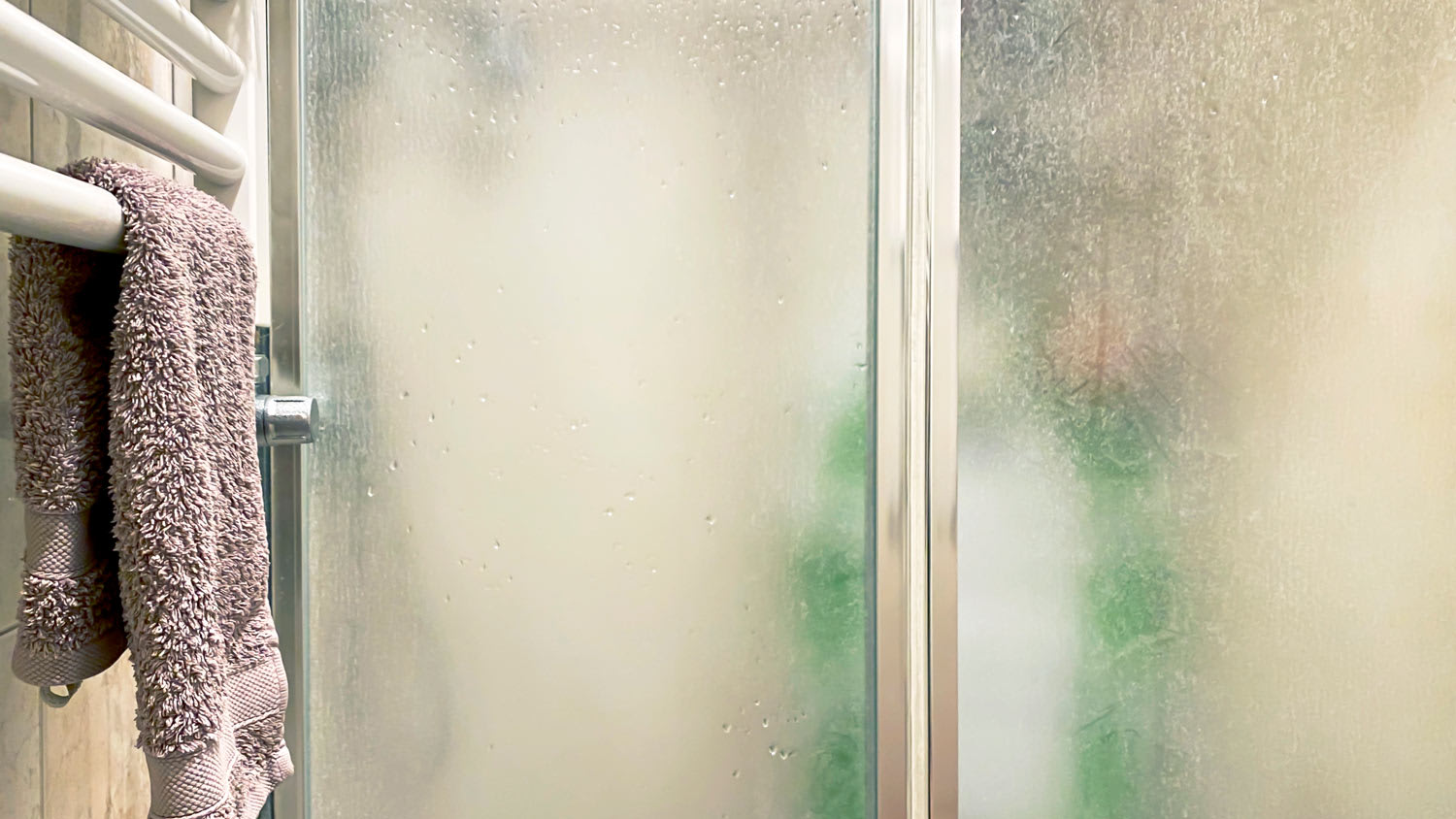 A towel on a radiator next to a shower cabin