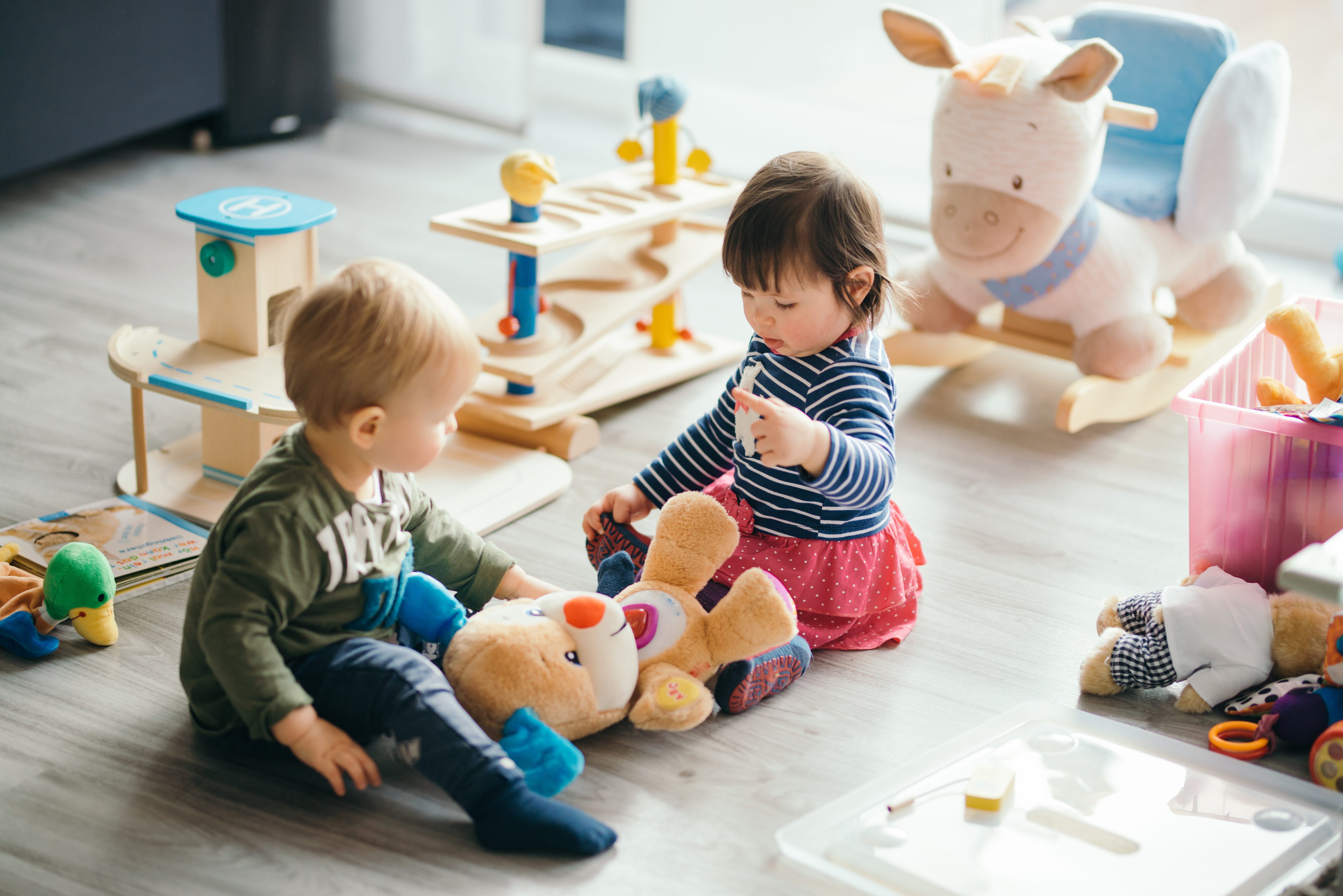 Little boy and little girl playing with toys in child’s room