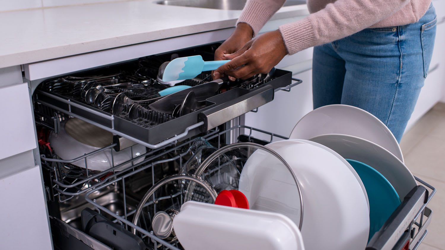 A woman unloading clean cutlery from the dishwasher