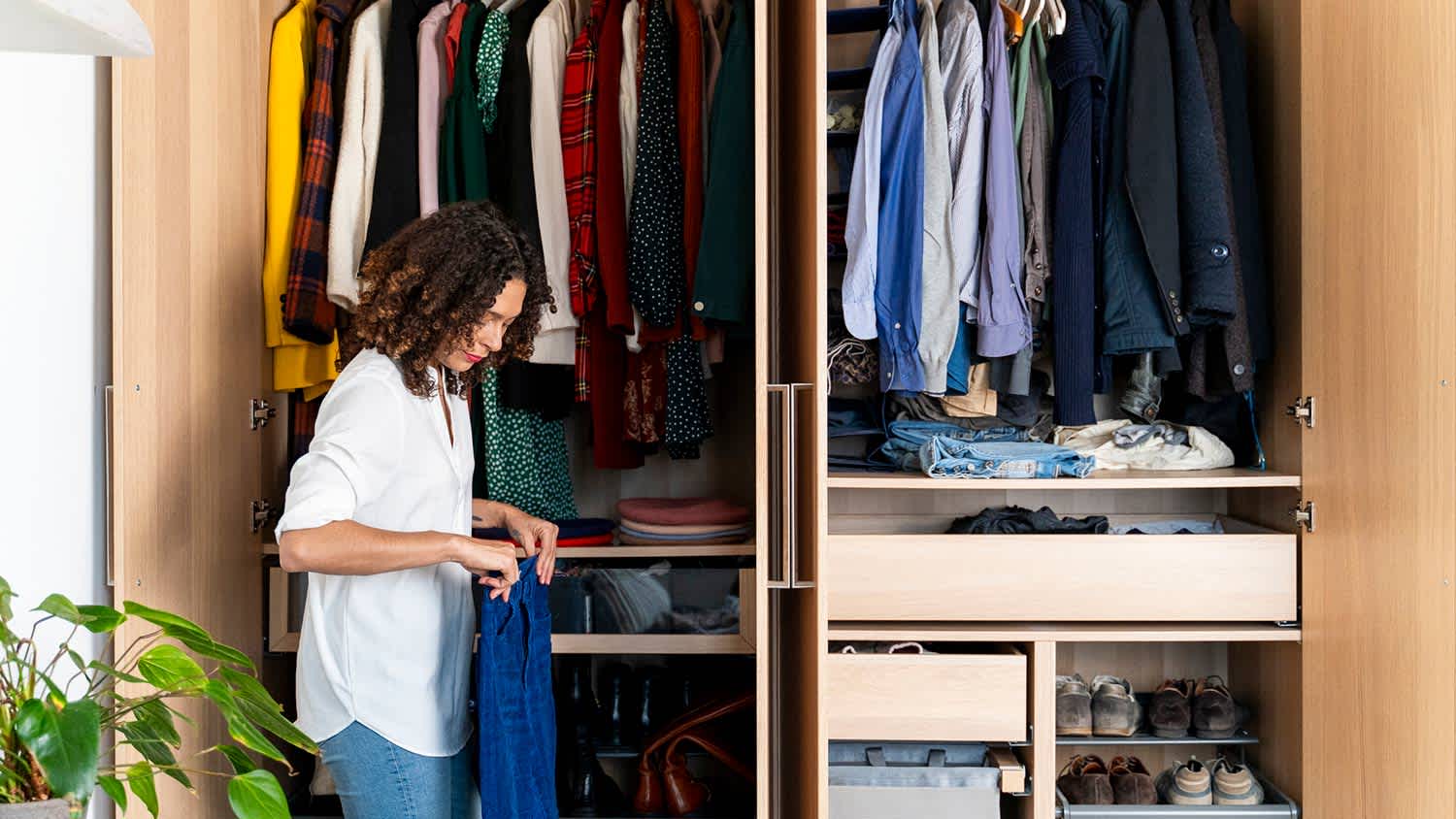 Woman organizes her wardrobe in cabinet closet