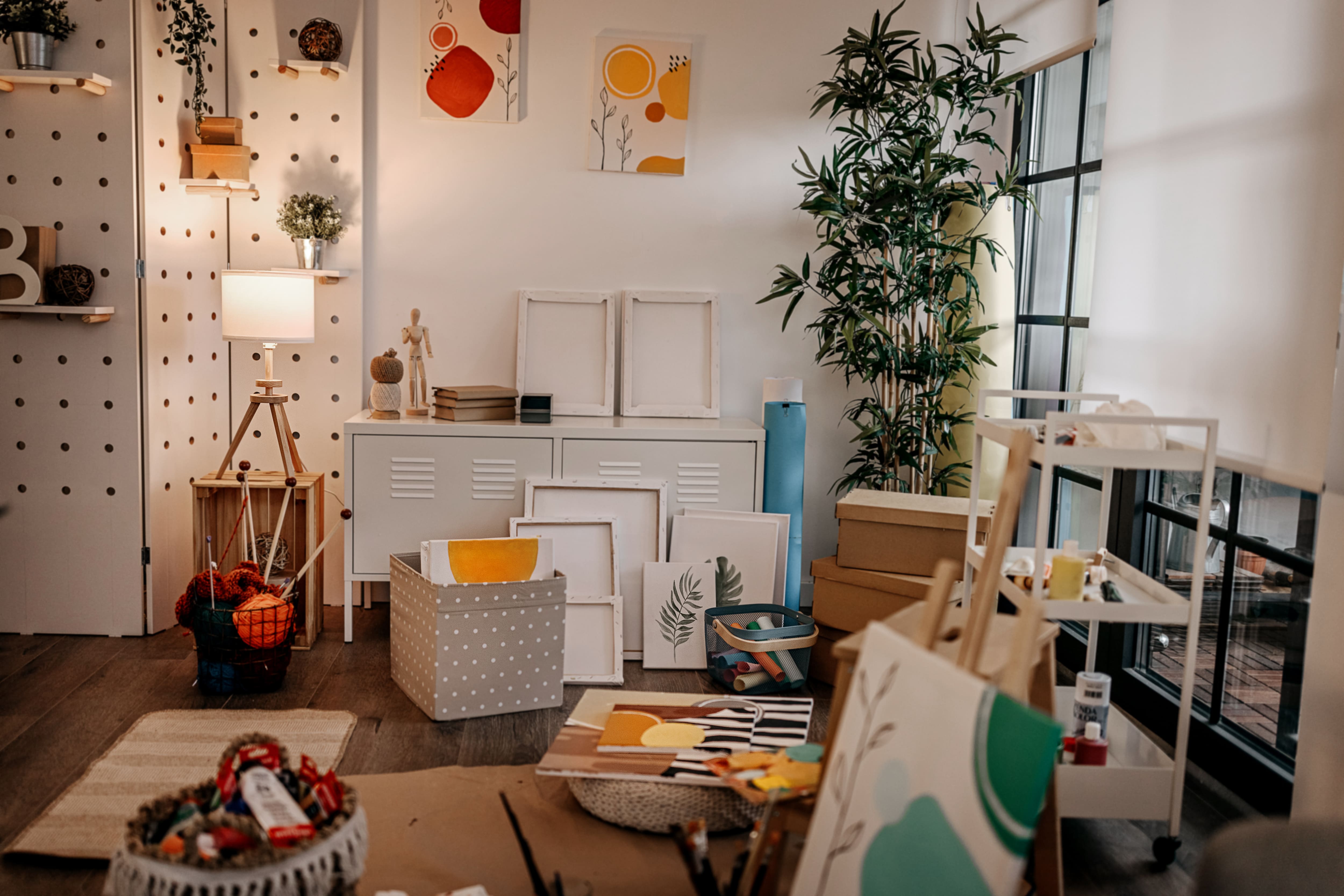 Craft room with window, desk, easel, tree, cabinet, and pegboard wall