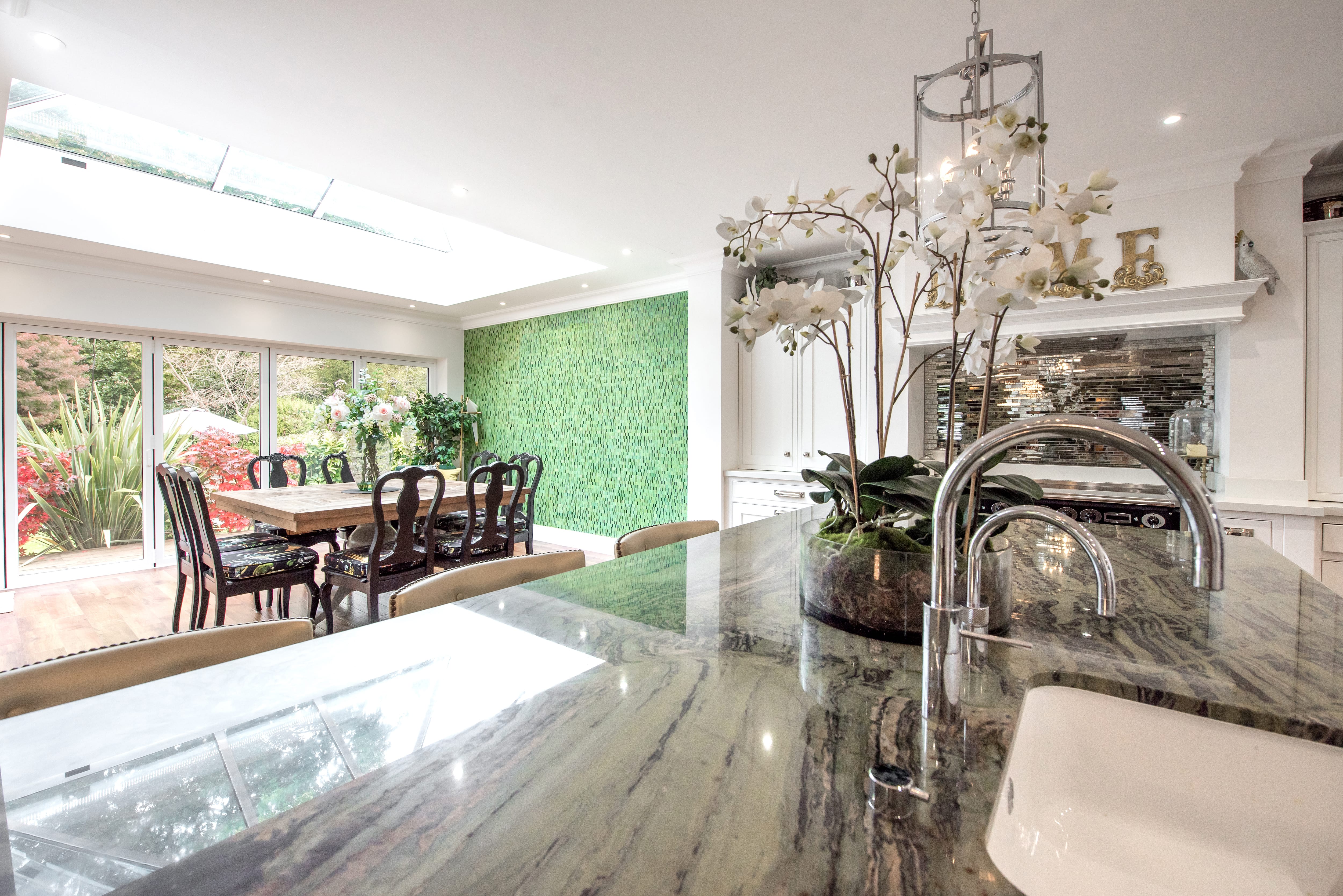 White kitchen with a green accent wall separating the dining room