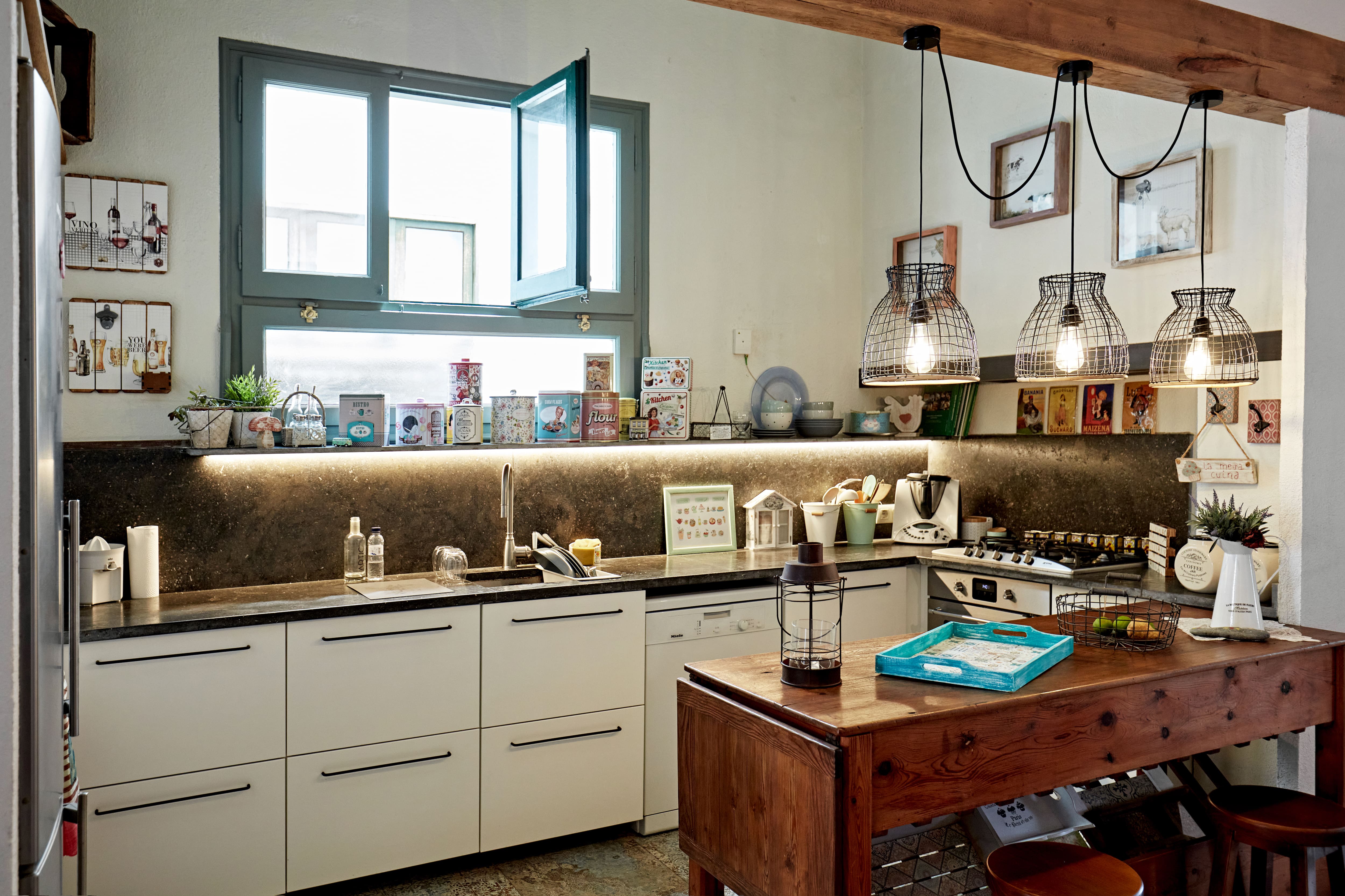 A black and white kitchen with an three metal cage pendant lights