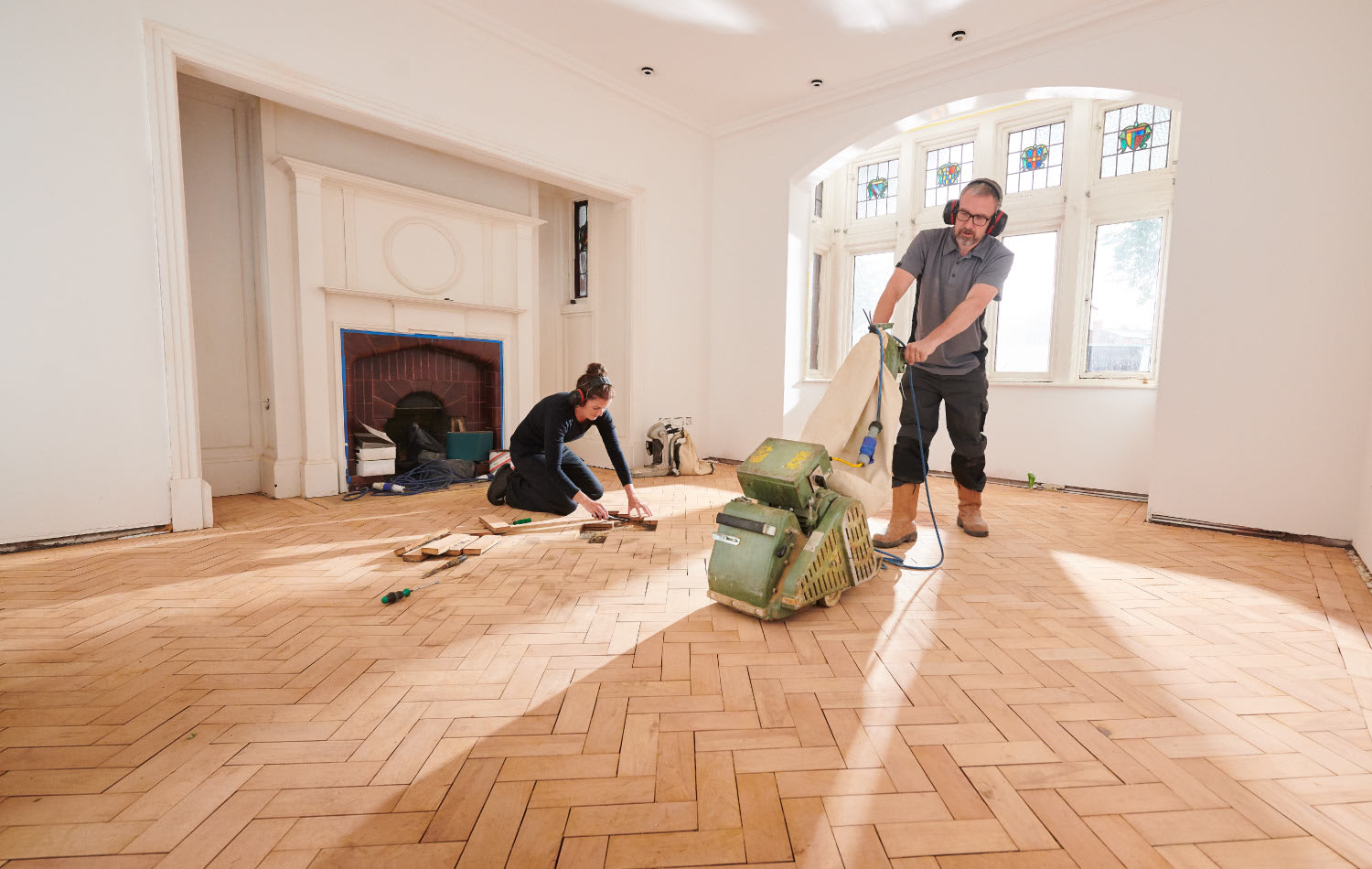 A man sanding a hardwood floor