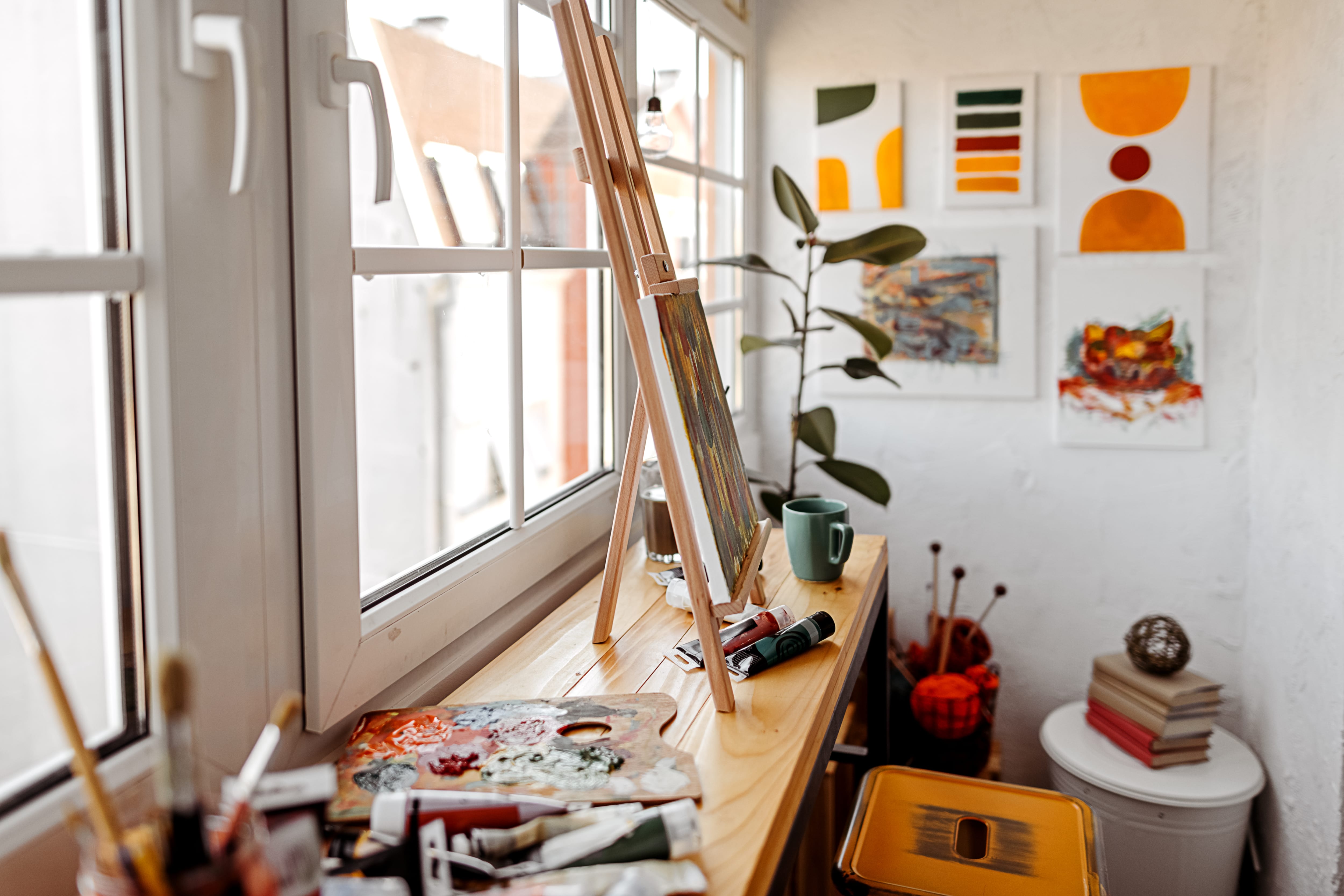 Home craft room with work table, stool, painting, easel, and art supplies