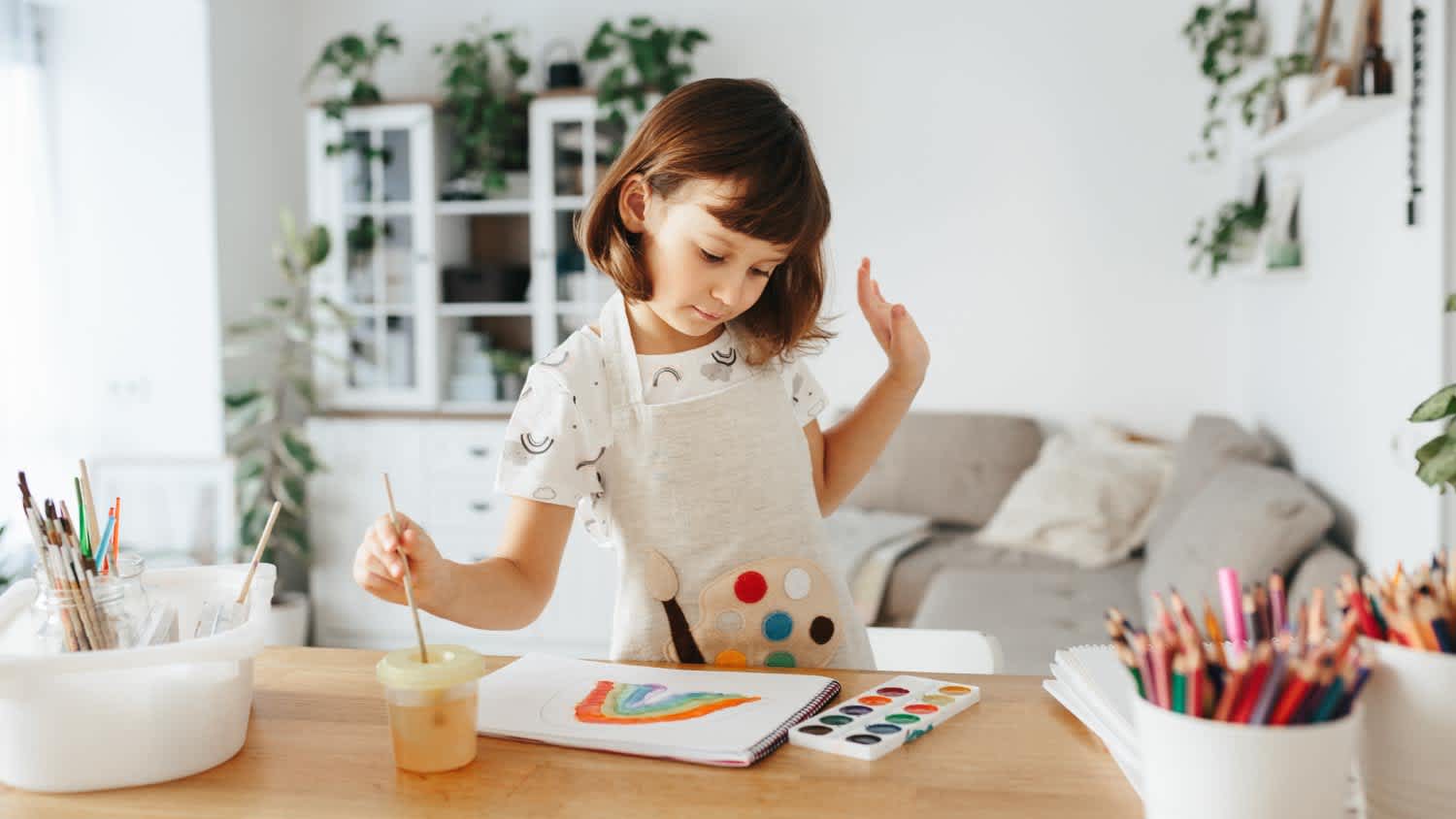 Girl painting watercolor rainbows at table