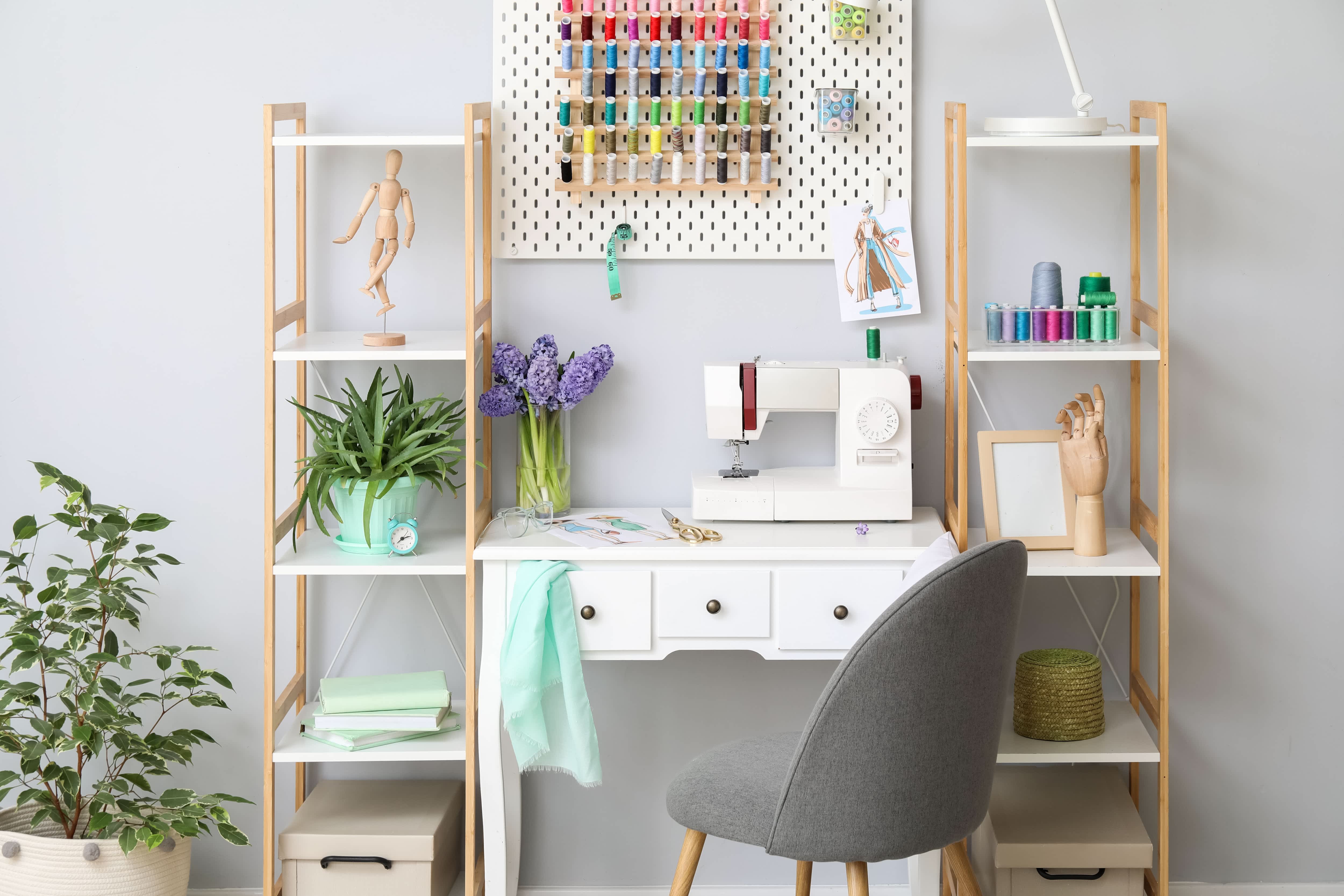 Bright craft room with pair of ladder shelves, desk, chair, and sewing machine