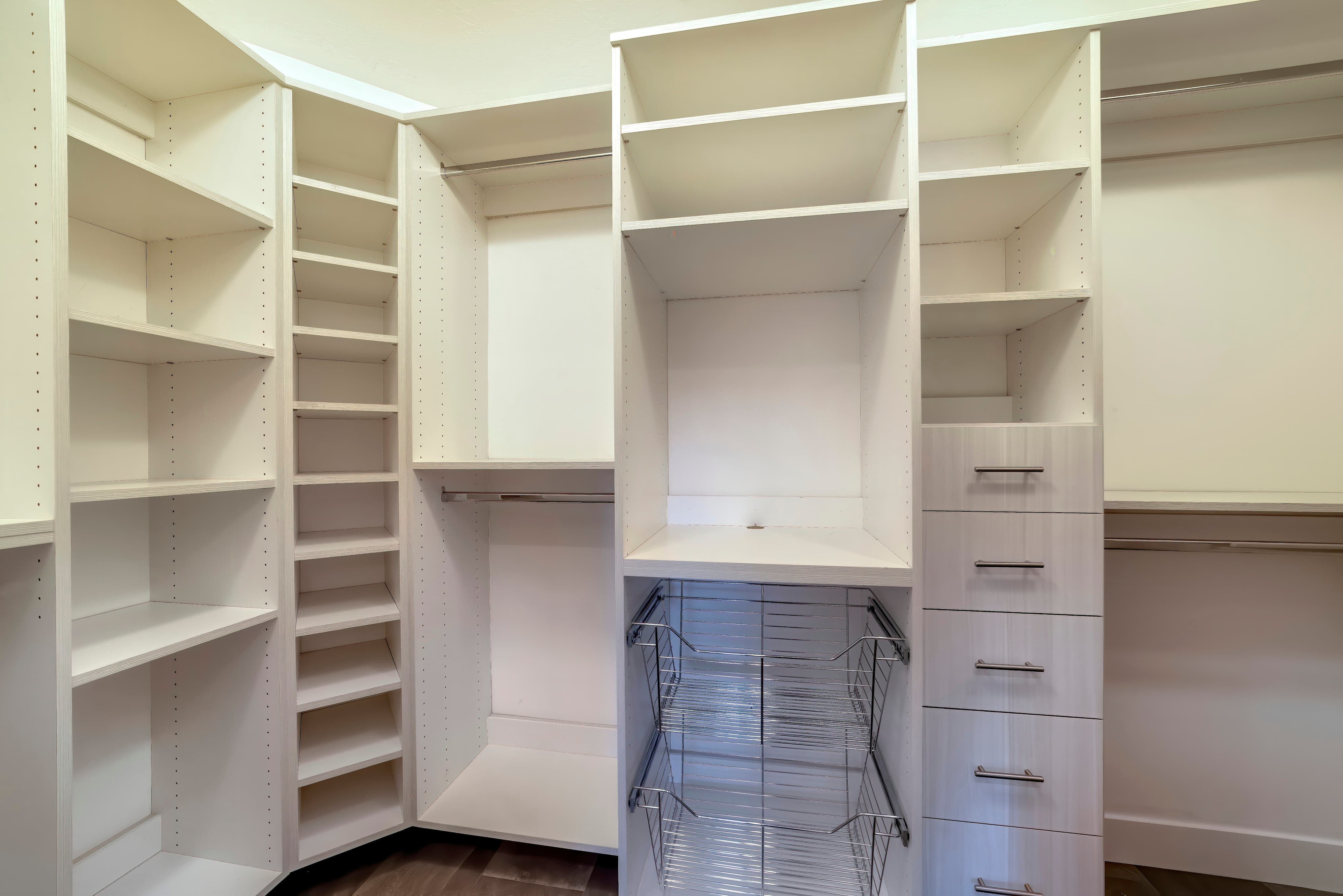 A white walk-in closet with metal baskets for storage
