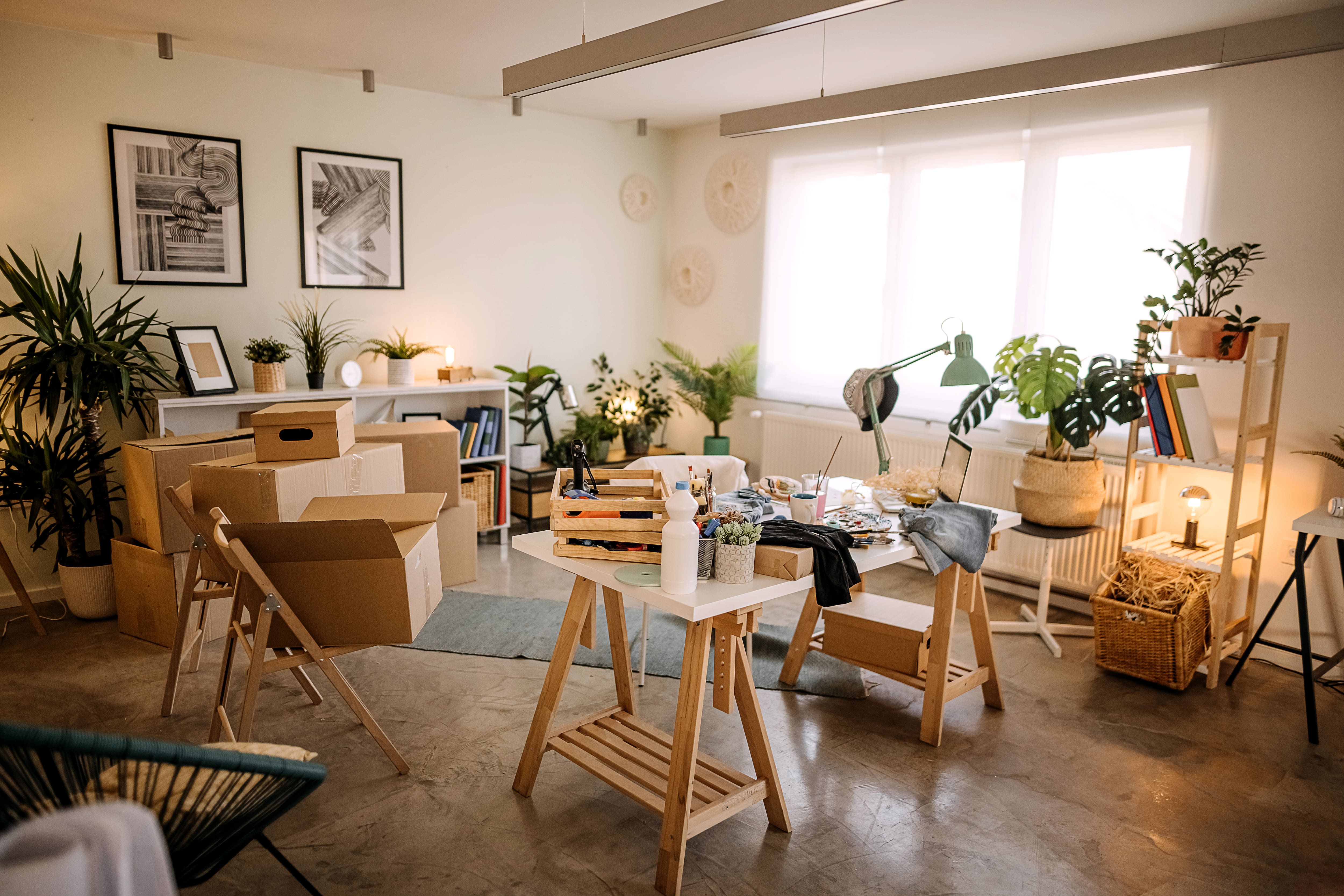 Cozy, white craft room with wooden furniture, art supplies, and plants