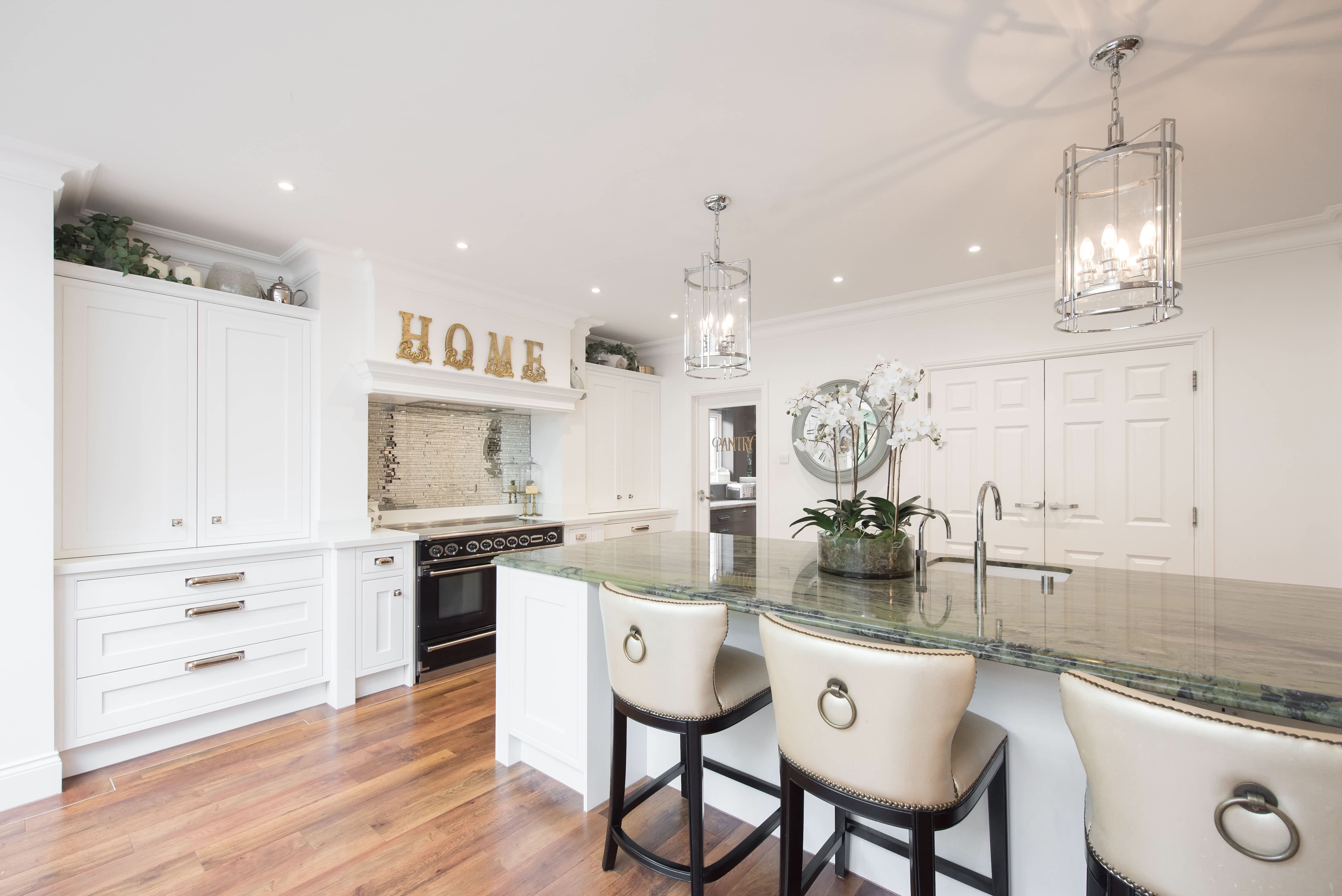 A kitchen with an island, champagne chairs, gold lettering, and mixed metal fixtures