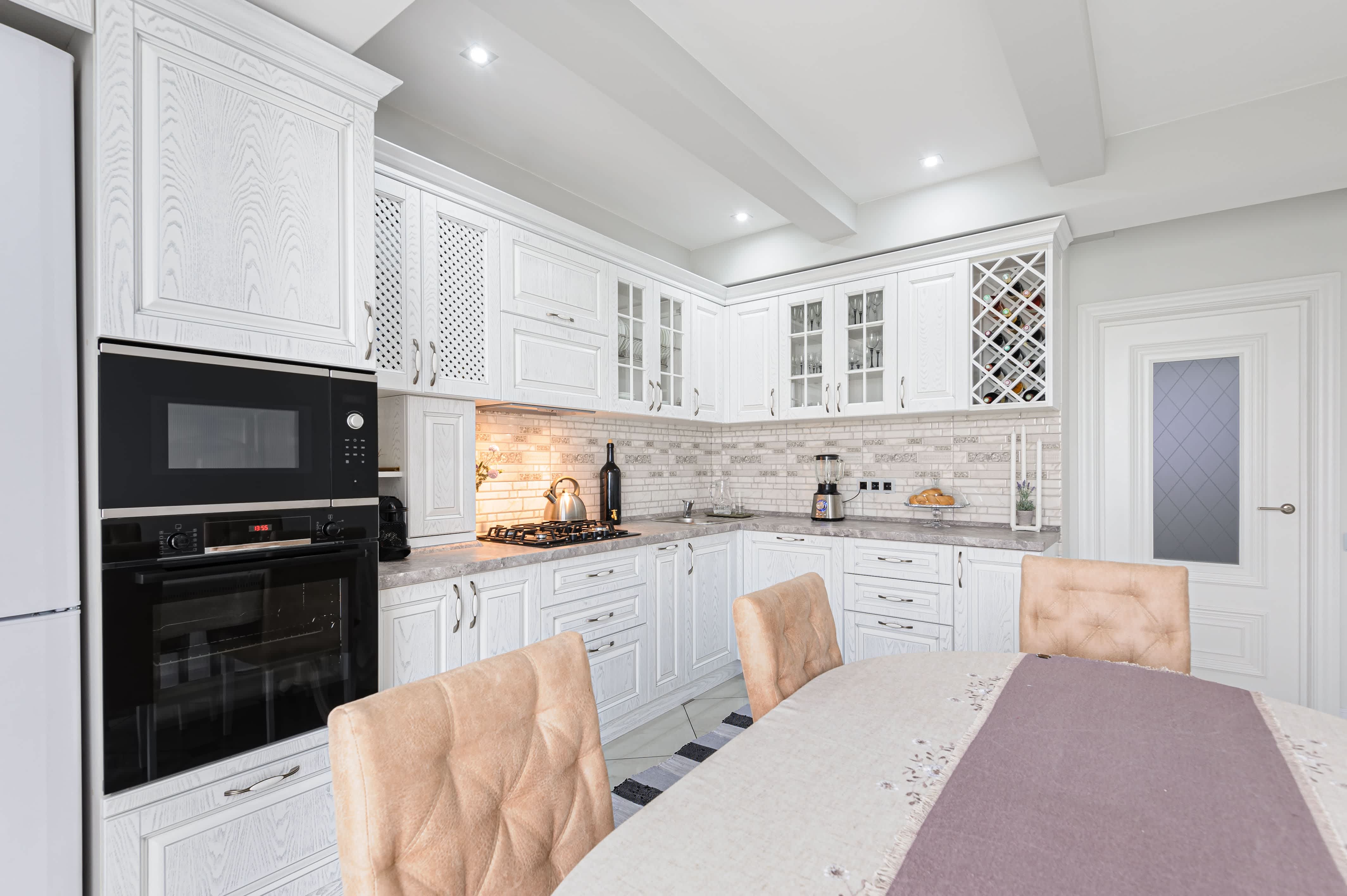 A modern country kitchen with mosaic backsplash, table, and chairs