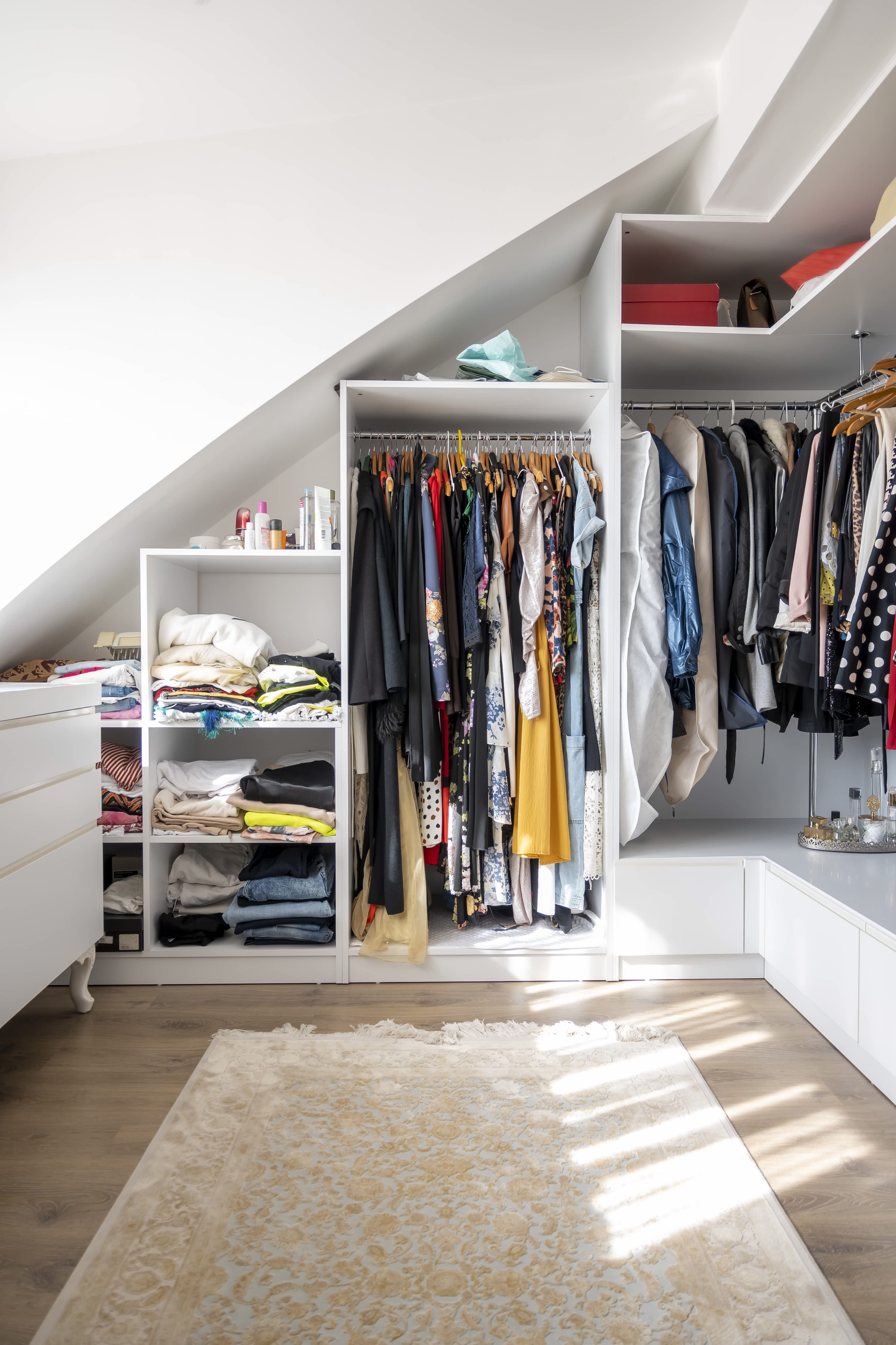 A brightly lit walk-in closet with a patterned rug on the floor