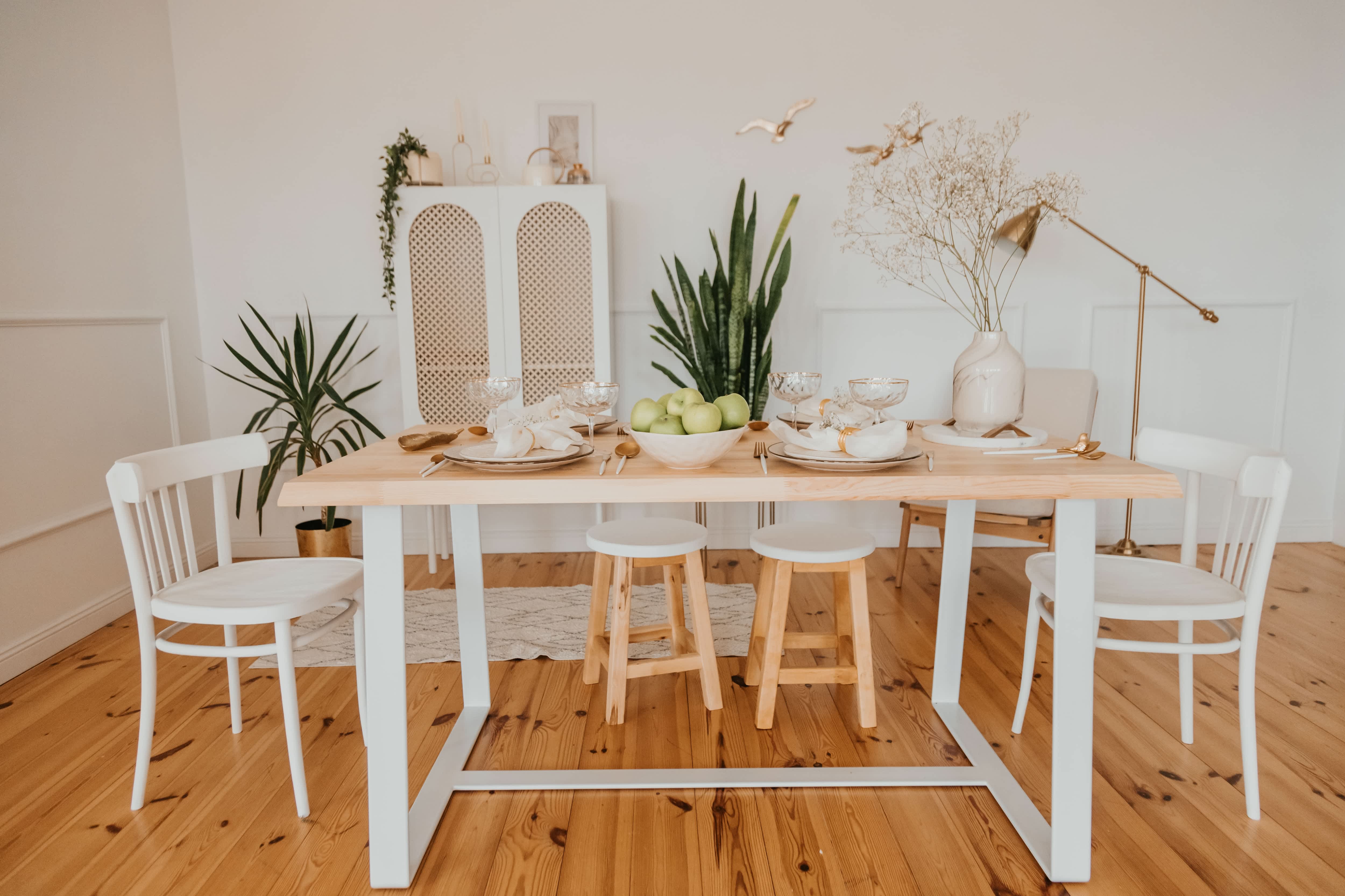 A dining area with a light furniture, fancy dishware, and rose gold accents