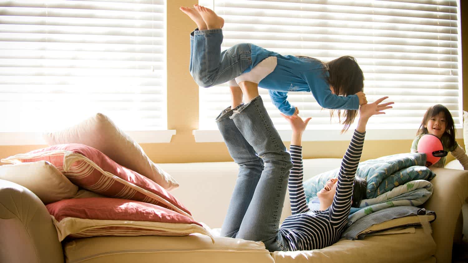 A young mother playing with her daughters in the living room