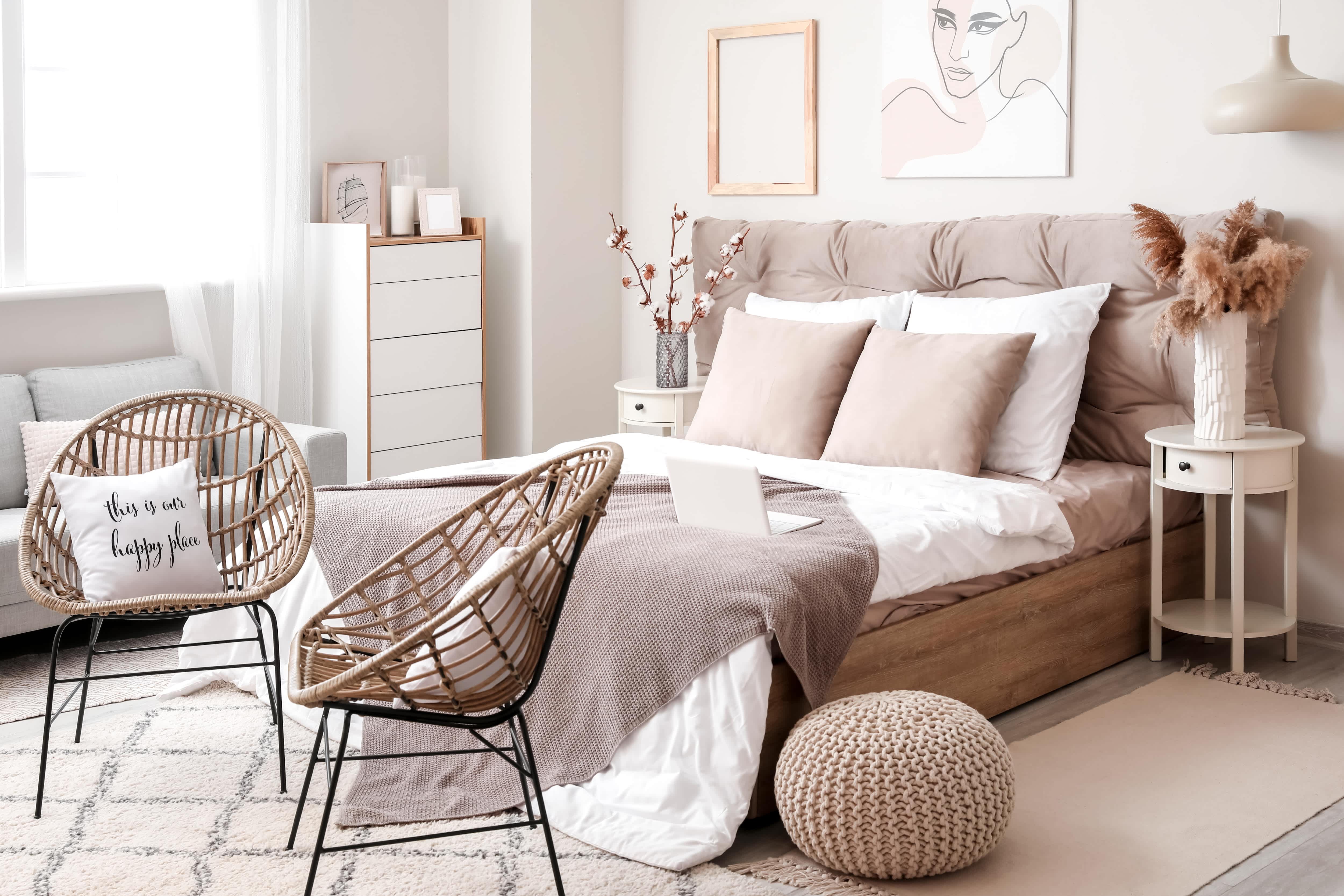 Modern bedroom with wall art, a pink headboard, a pouf, and two woven basket chairs.