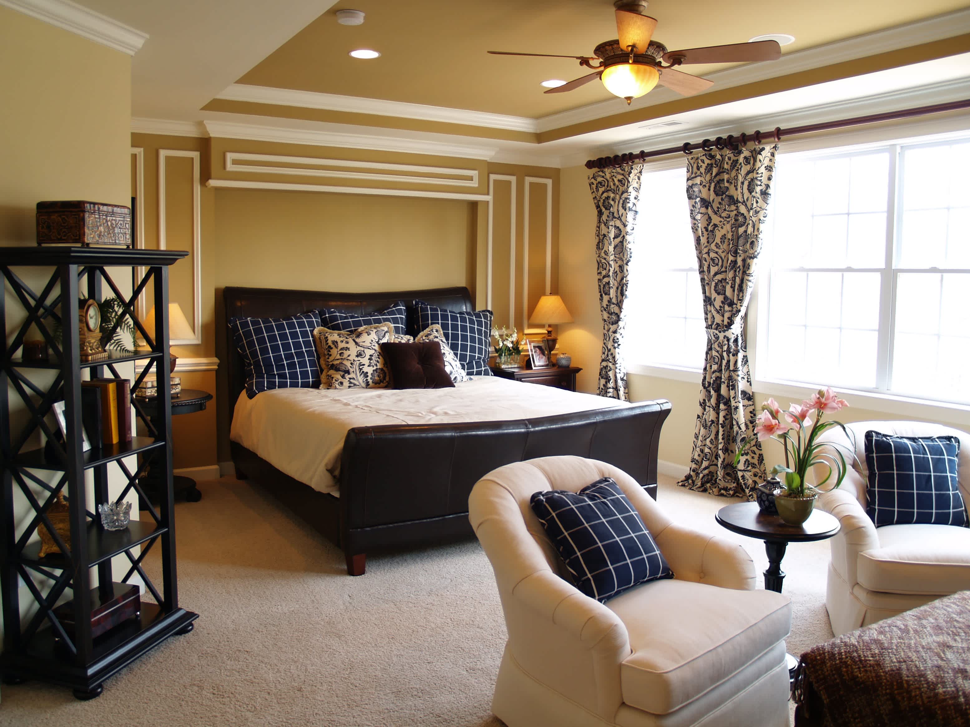 Bedroom with dark leather bed, windows, paisley curtains, gold walls, and gold painted coffered ceiling