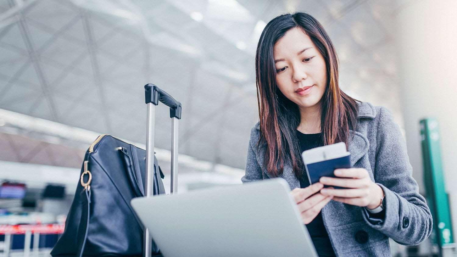 Woman holding passport and using laptop at the airport