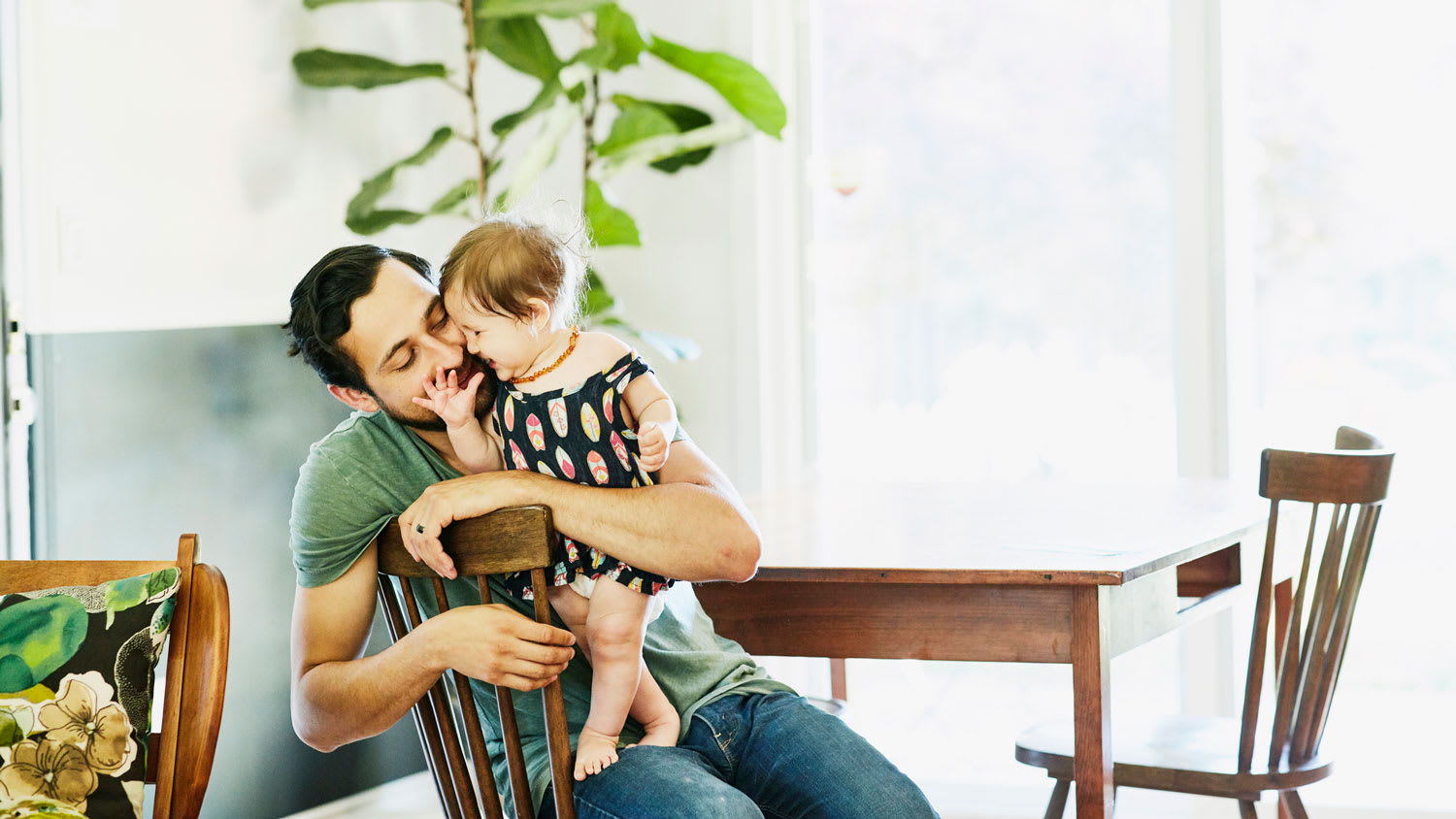 A father holding his daughter sitting at the wooden dining table