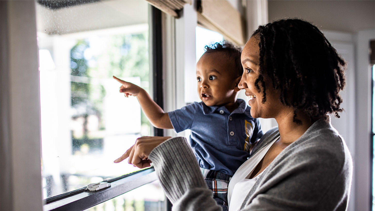 A mother and child look out a window