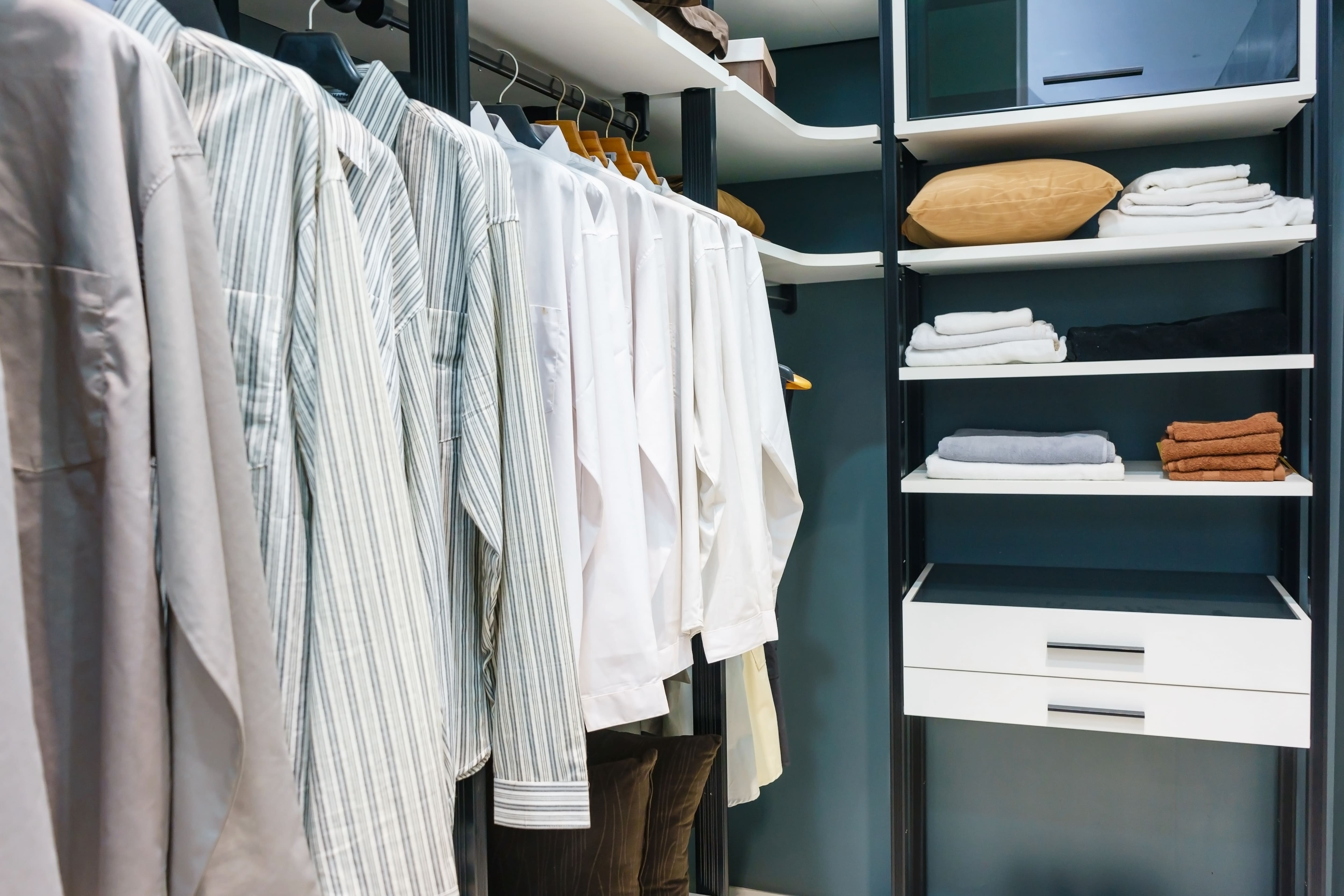 An organized closet with color coded shirts