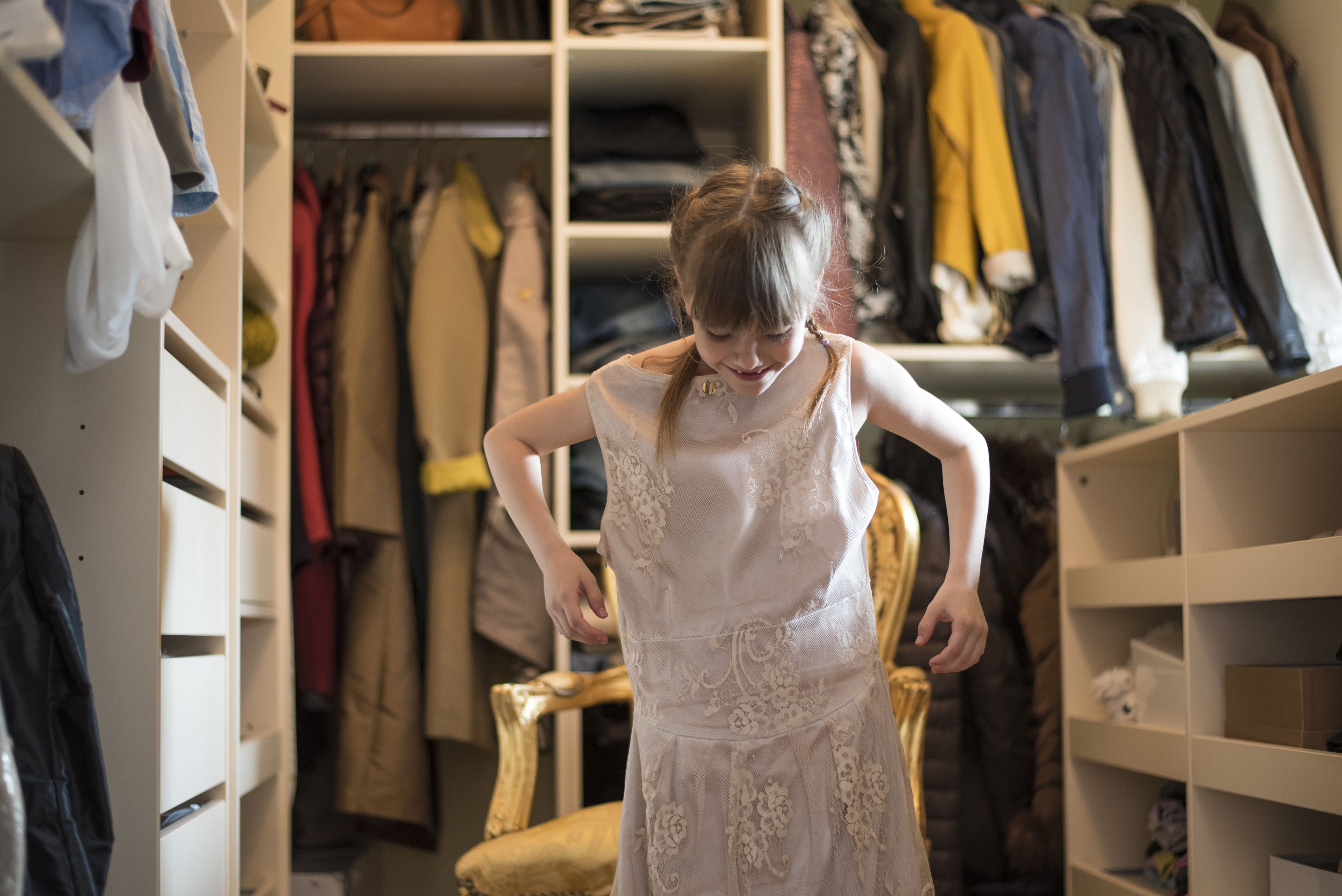 A little girl plays dress-up in a walk-in closet