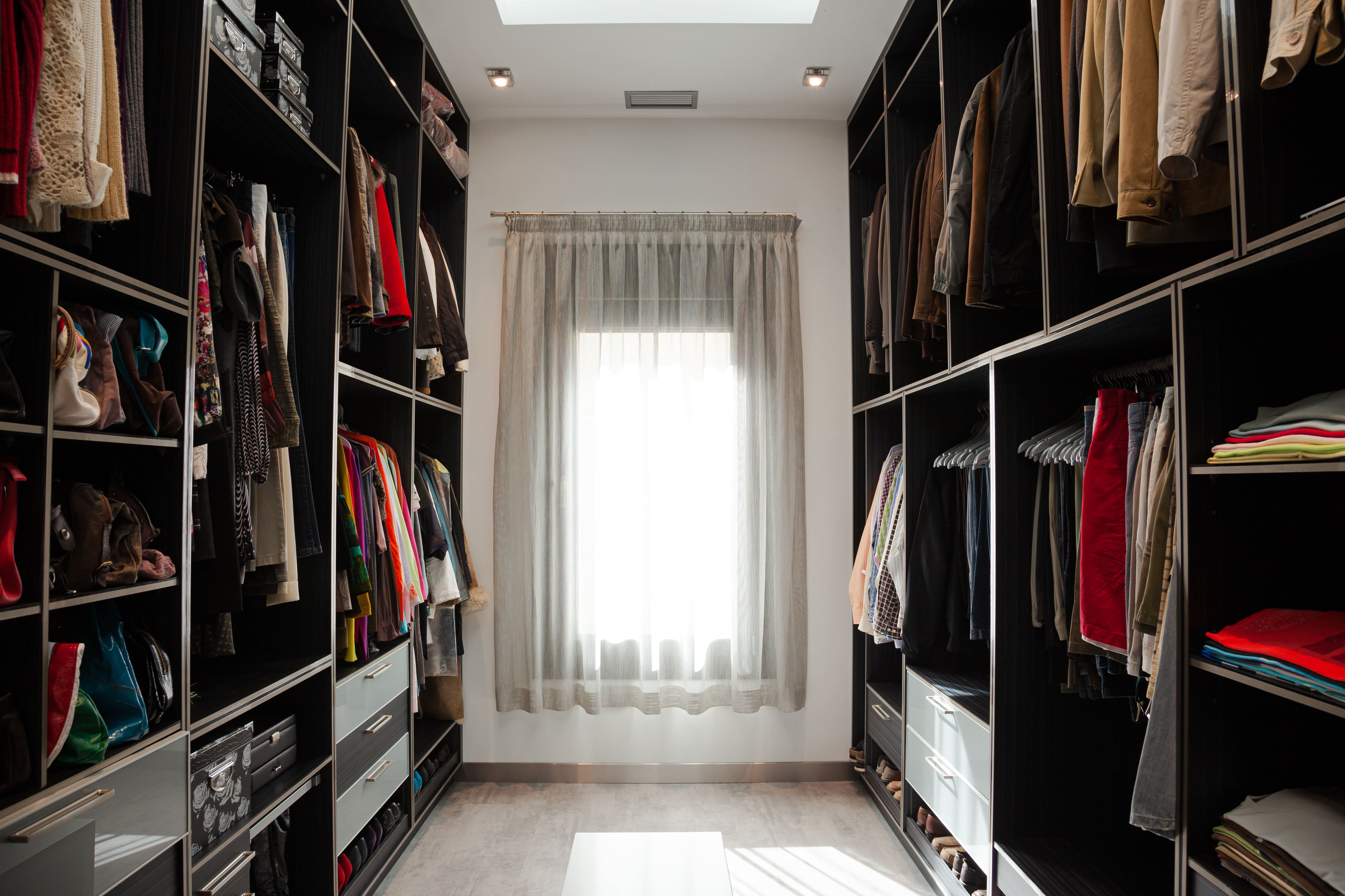 A narrow walk-in closet with a large window lighting up the space