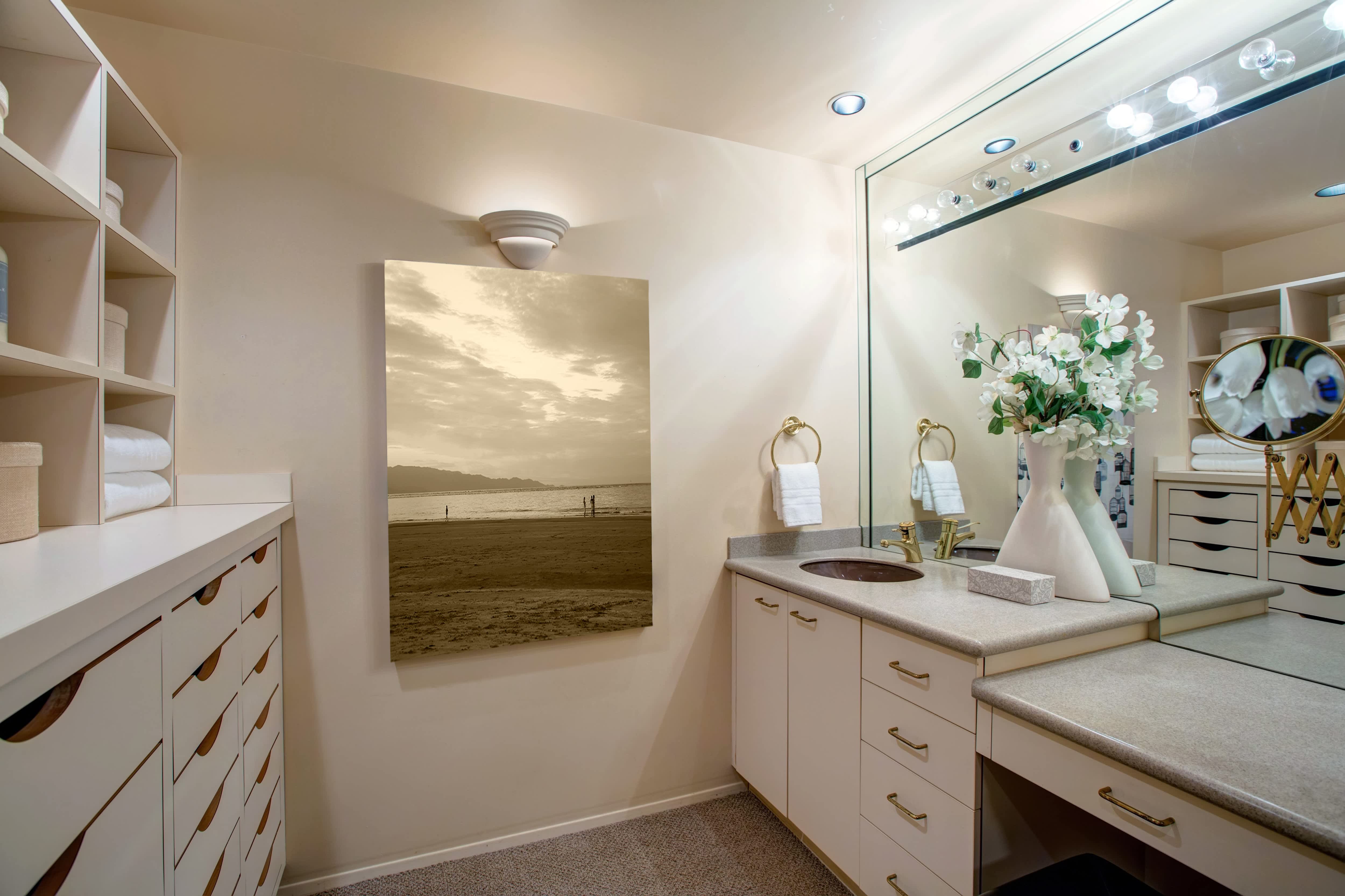 A small walk-in closet with a large vanity and mirror
